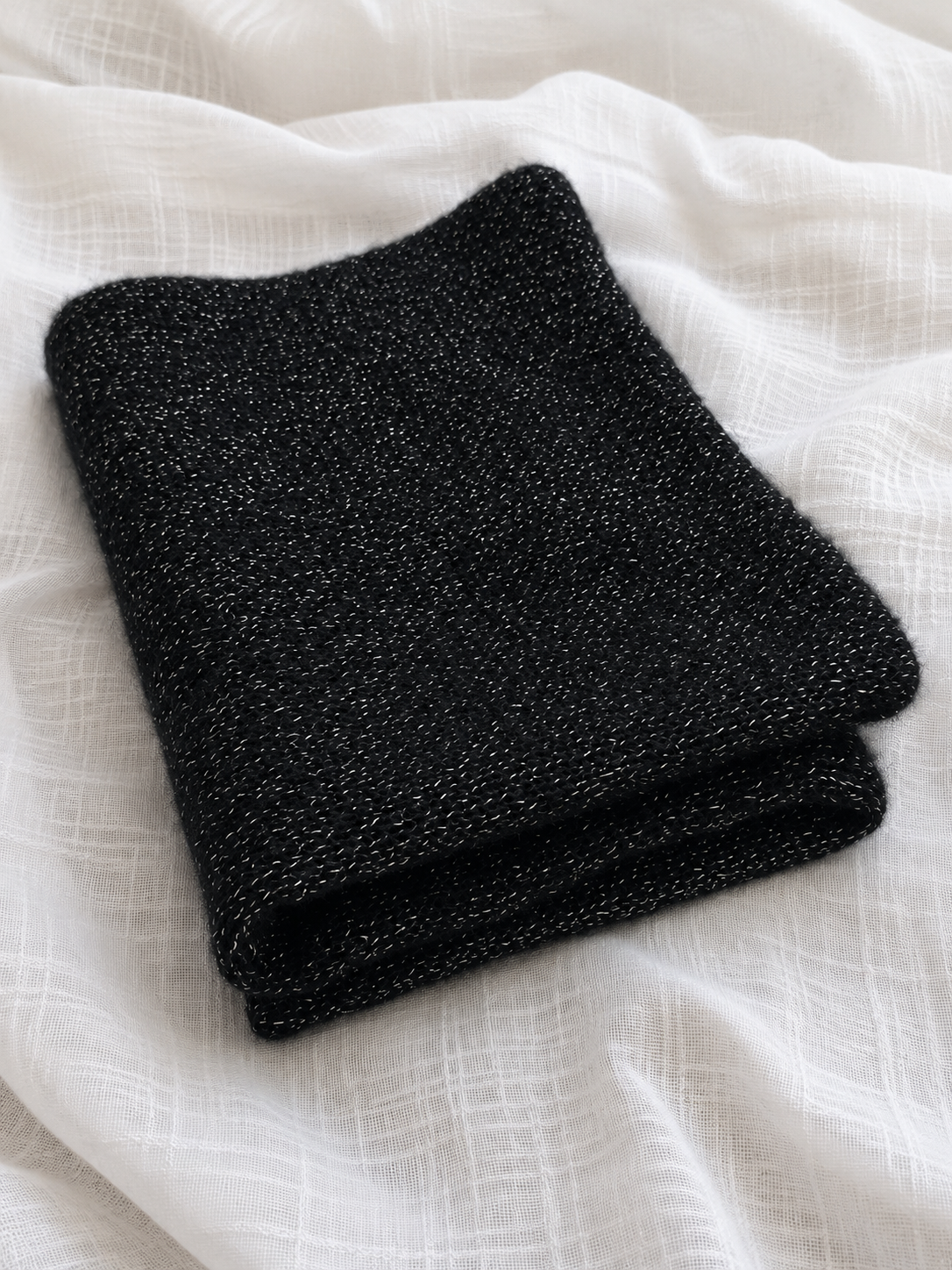 Soft black infinity loop scarf showing lightweight open knit construction