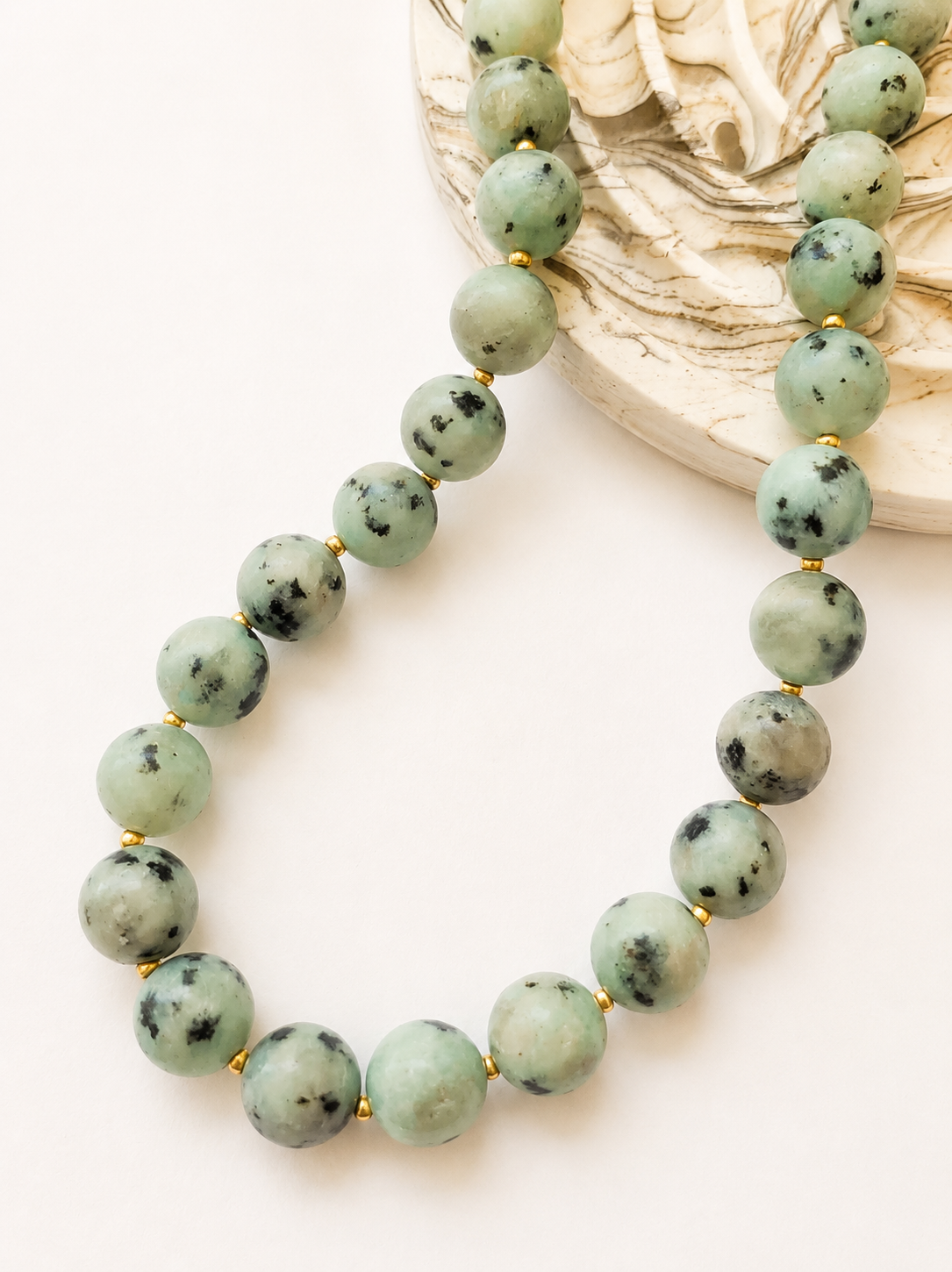 Kiwi jasper necklace styled beside a neutral marbled jewellery tray