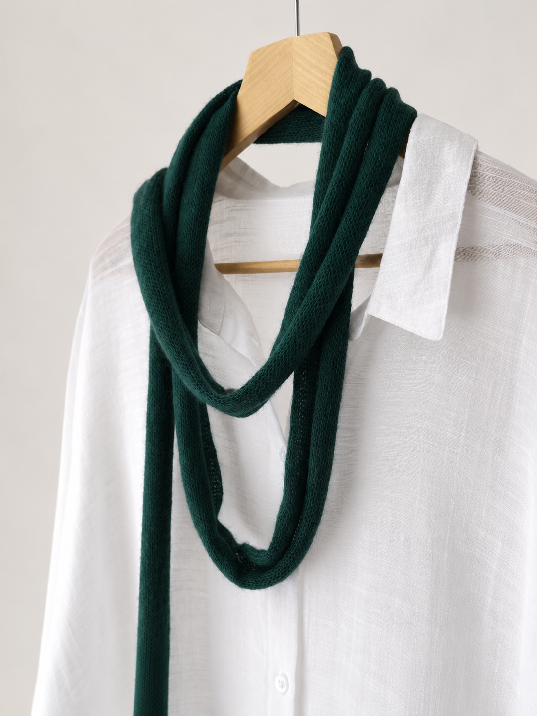 Angled view of handmade forest green skinny mohair scarf on a white shirt.