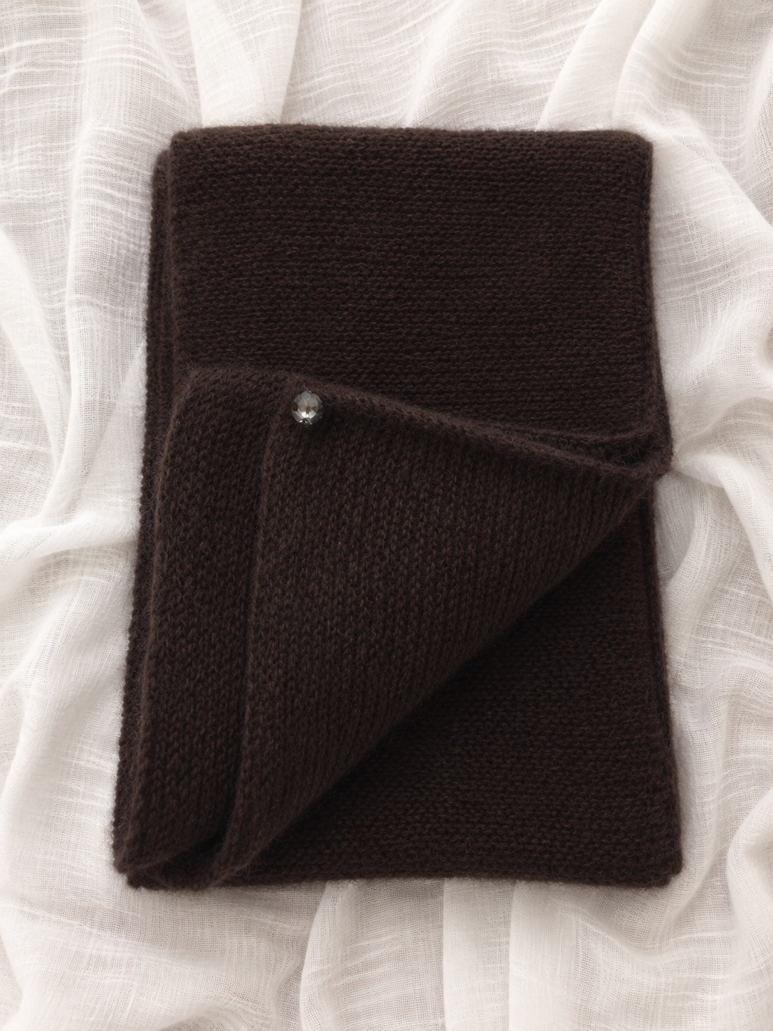 Folded Dark Brown silk mohair infinity scarf on white linen fabric.