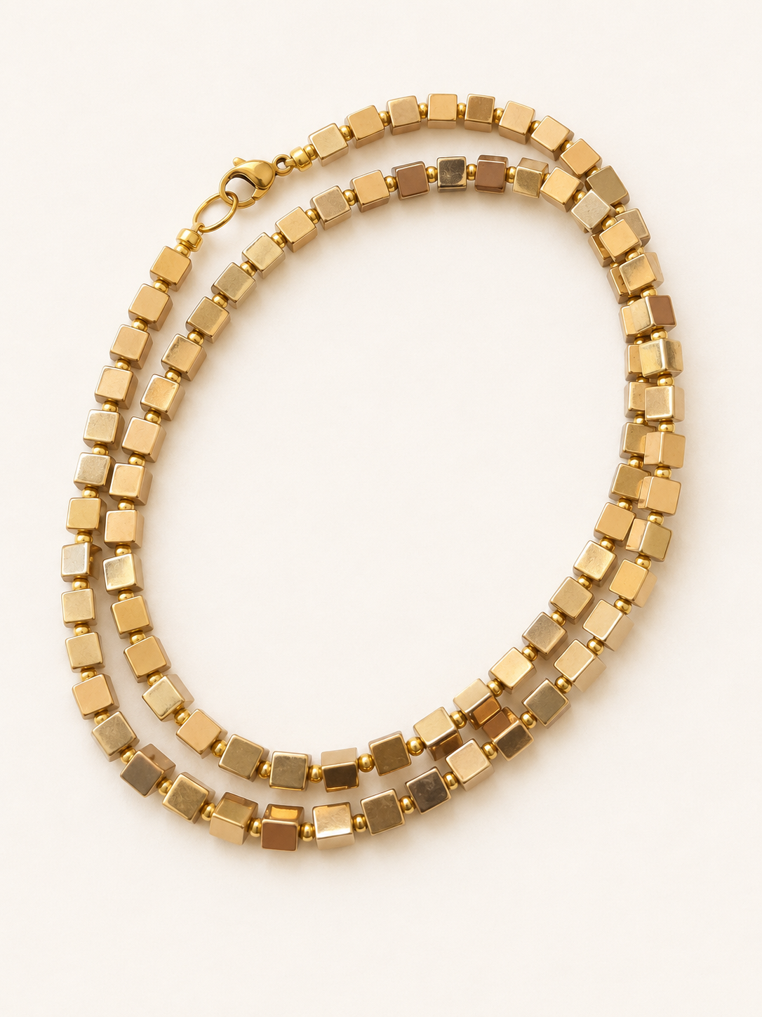 Coiled gold hematite necklace showing square beads, golden spacers and stainless steel clasp