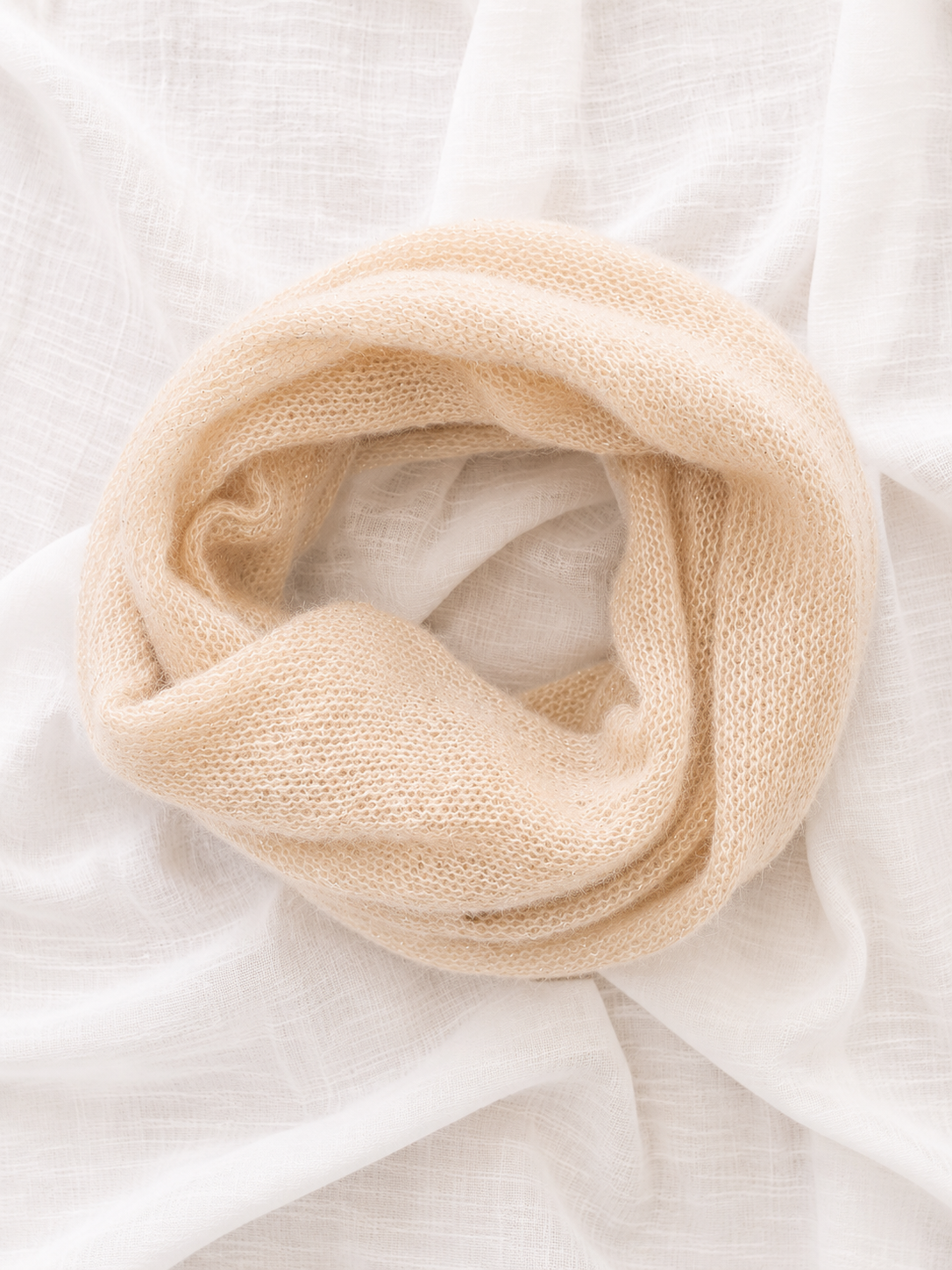 Rolled Light Champagne Infinity Scarf on a white fabric background.