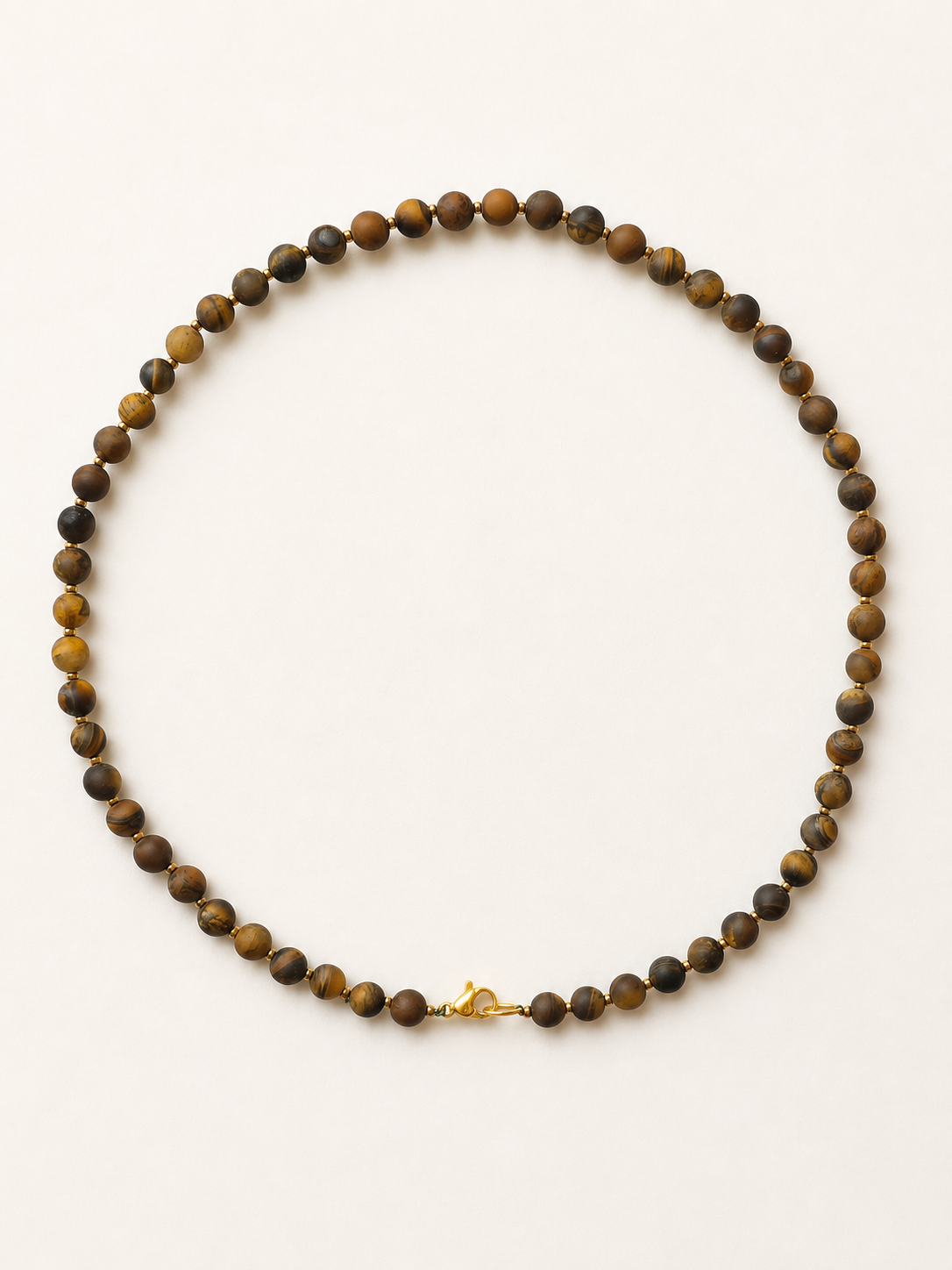 Matte tiger eye necklace with gold accents and gold-colour lobster clasp on a warm ivory background