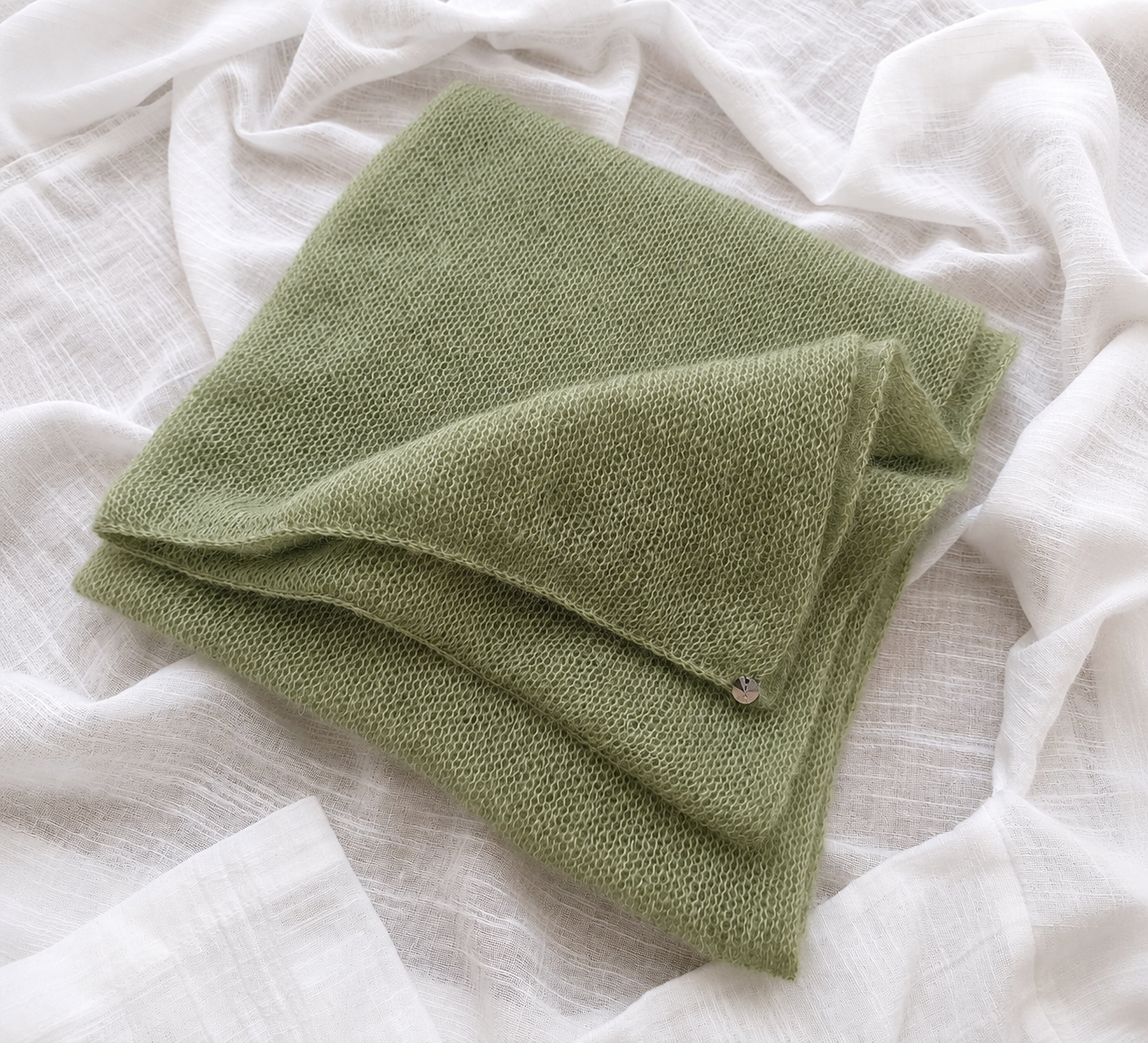Folded Soft Sage silk mohair scarf with crystal detail on linen fabric.