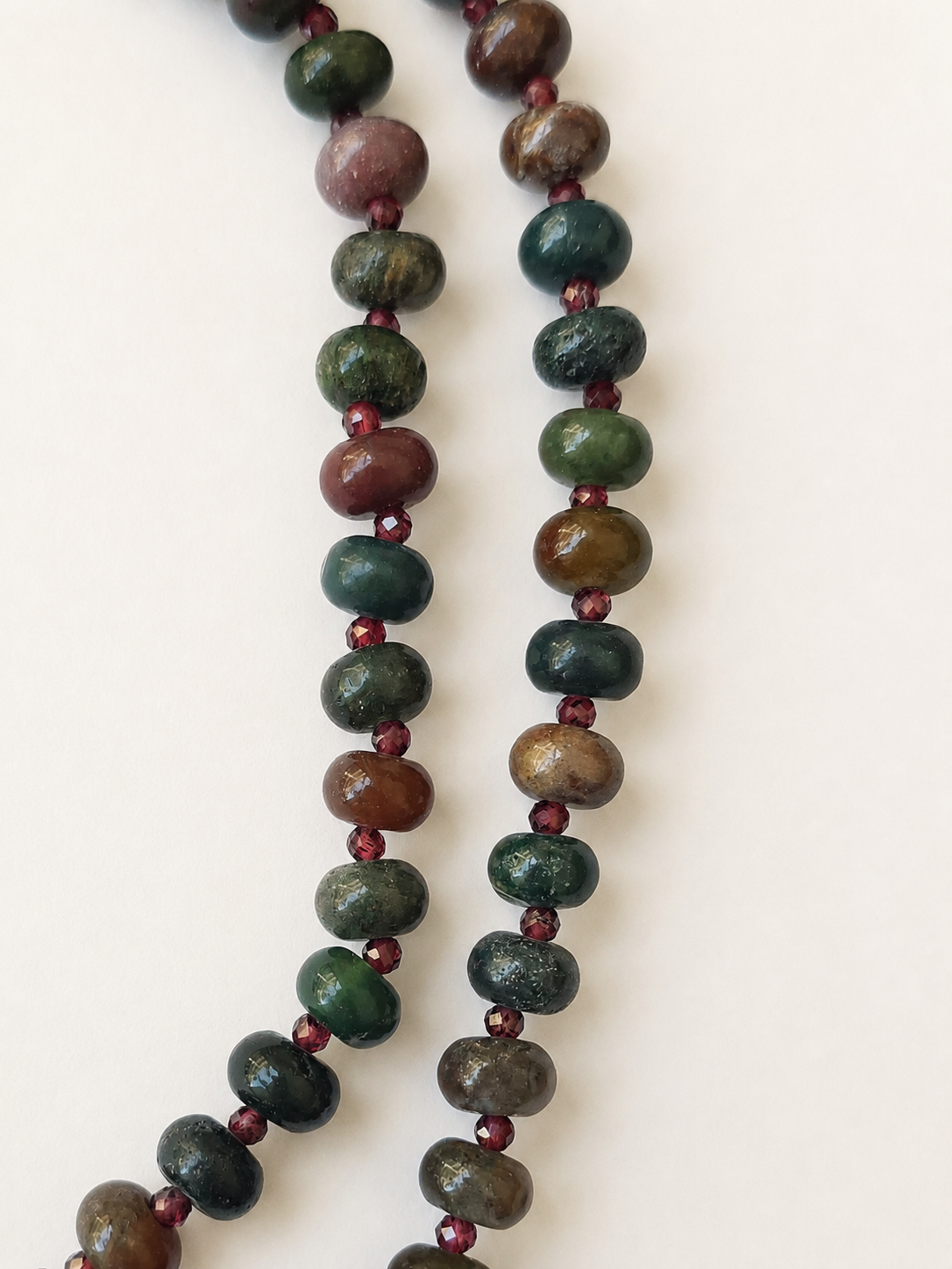 Detailed view of green, brown and muted red Indian agate beads with burgundy faceted accents