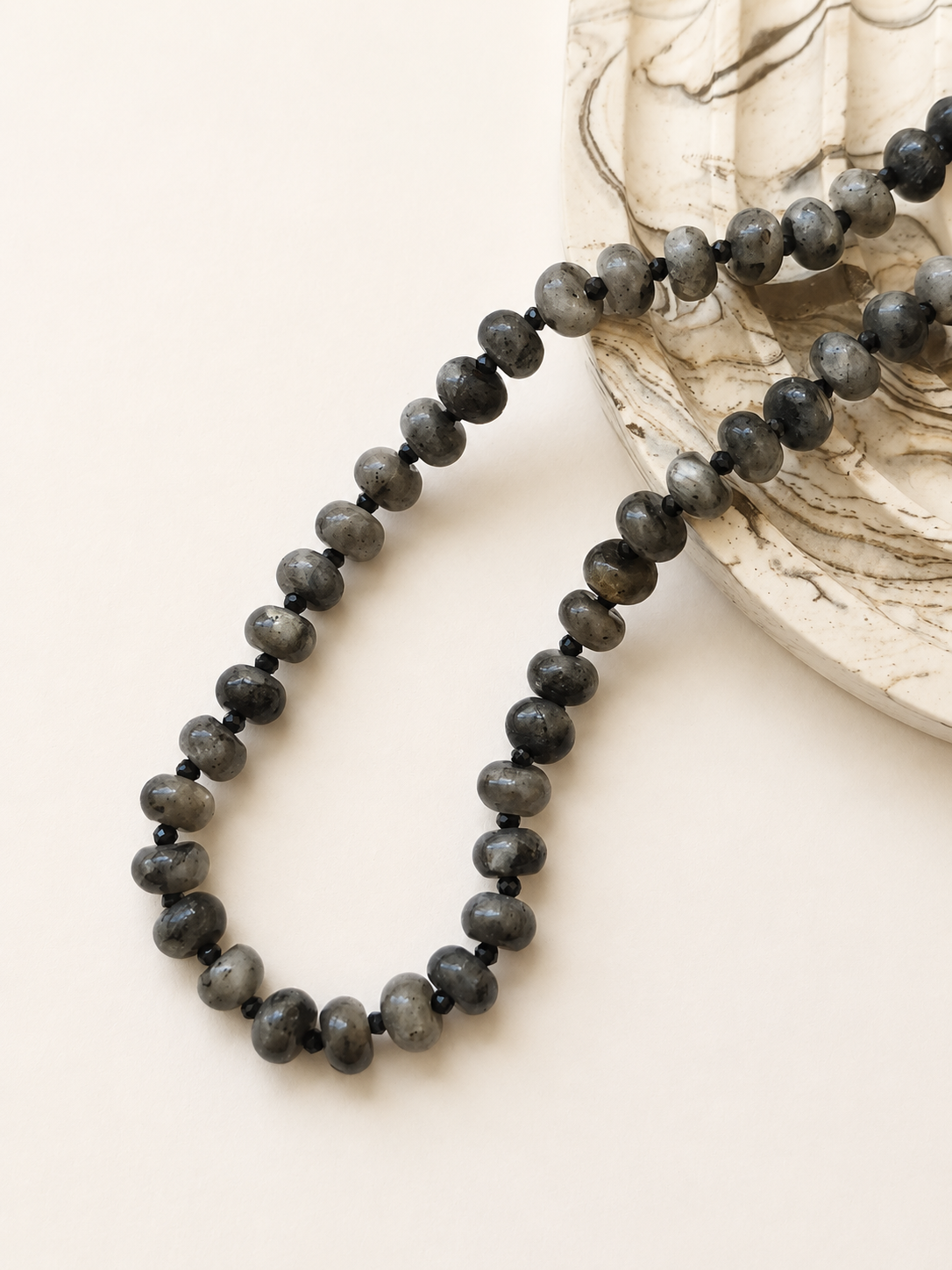 Labradorite rondelle necklace styled beside a neutral marbled decorative object
