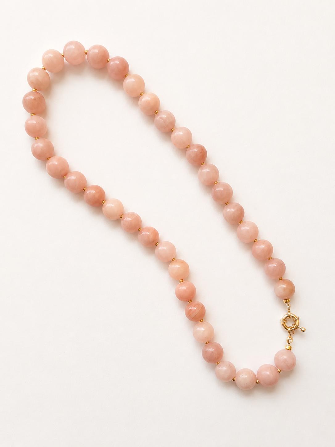 Blush pink jadeite necklace displayed lengthwise with a golden-colour spring ring clasp.

