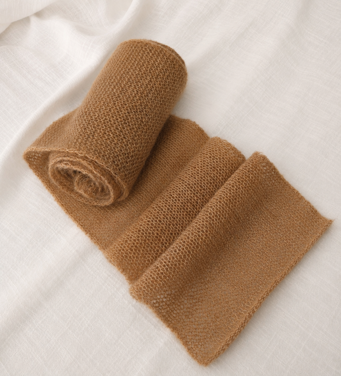 Rolled Warm Camel kid mohair scarf highlighting its lightweight knit.