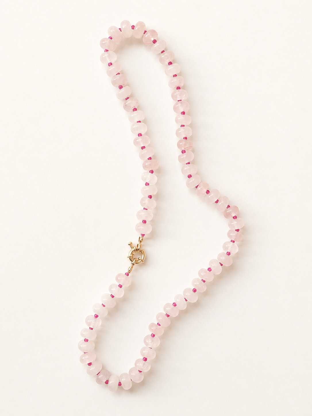 Full-length rose quartz necklace arranged in an elongated curve with fuchsia accents