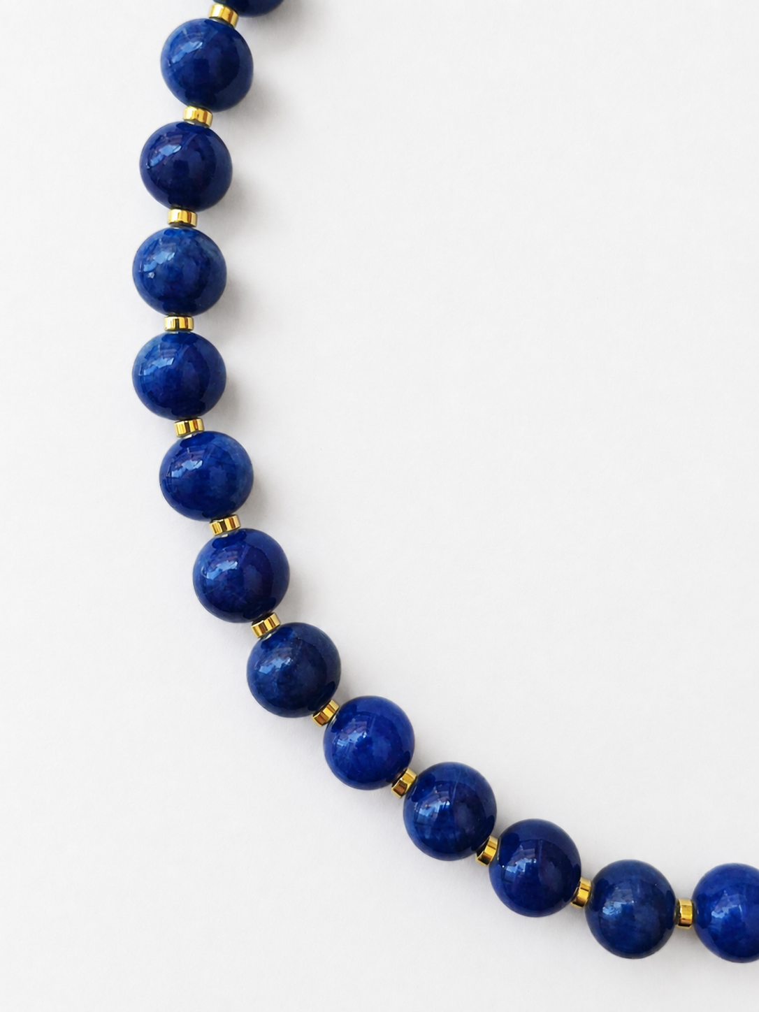Close-up of polished royal blue jadeite beads separated by small gold hematite spacers
