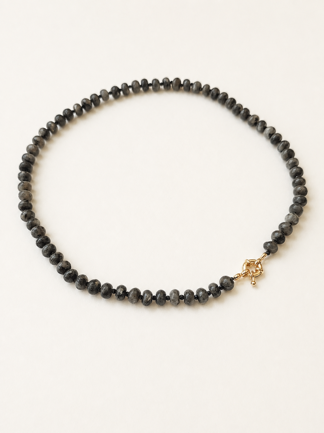 Angled full view of a smoky grey labradorite and faceted black spinel necklace