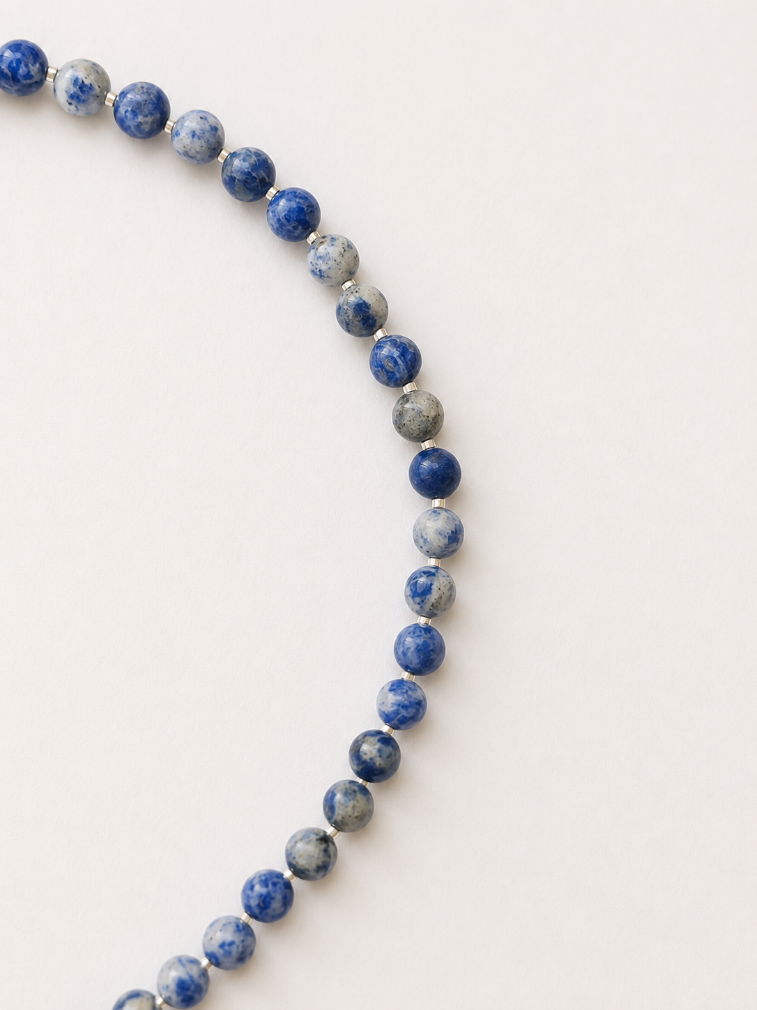 Close-up of blue, white and grey sodalite beads separated by silver Japanese Miyuki accents