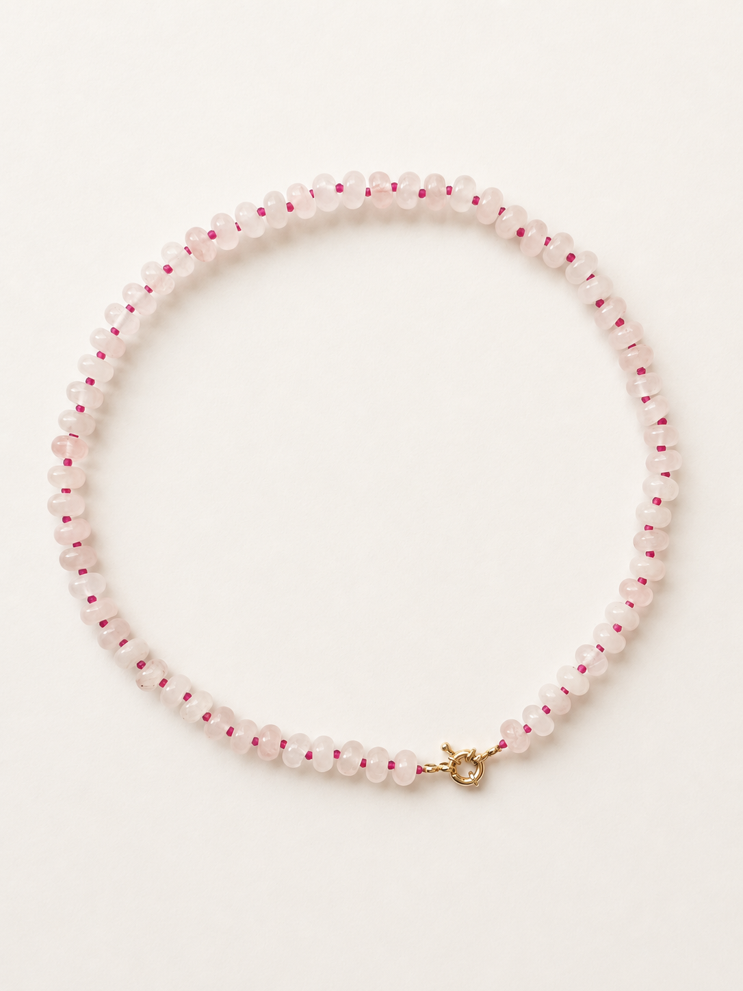 Rose quartz rondelle necklace with fuchsia glass accents and spring ring clasp on a warm ivory background