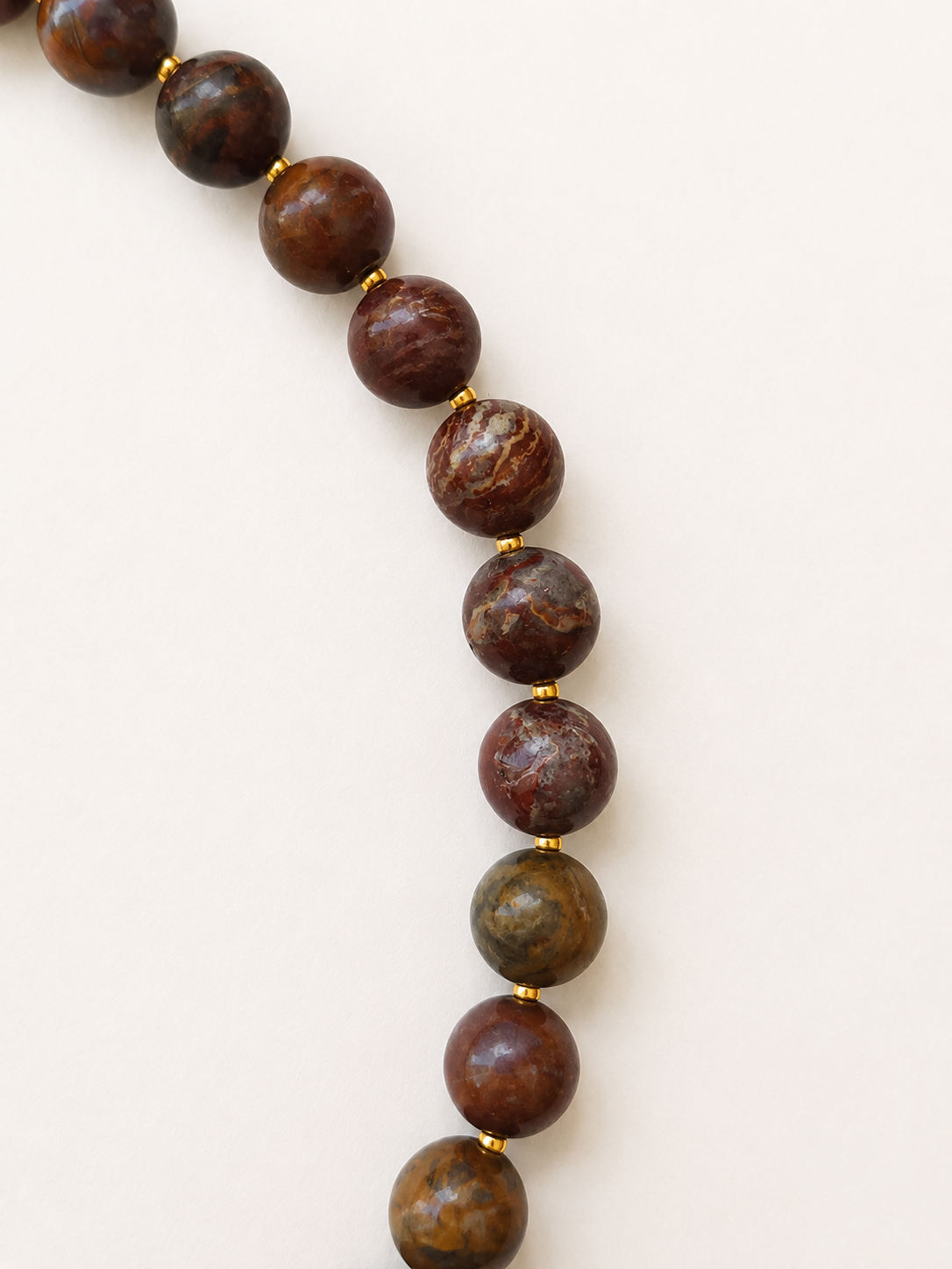 Close-up of naturally patterned brown, red and olive agate beads with Japanese Miyuki gold spacers