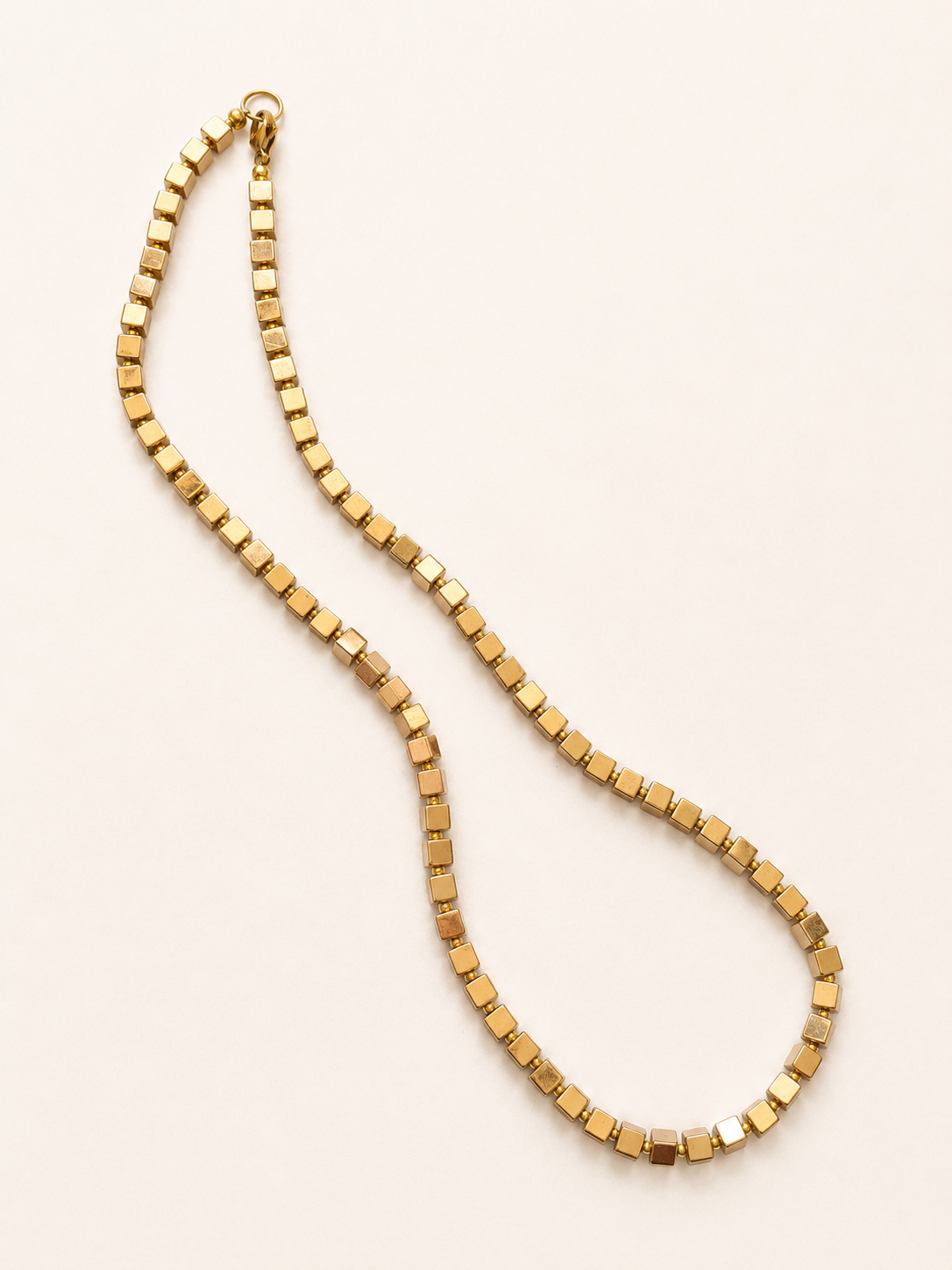Full-length arrangement of a geometric gold hematite cube necklace with a lobster clasp