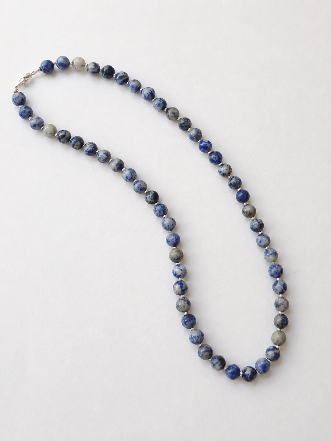 Sodalite necklace arranged lengthwise on a warm ivory background