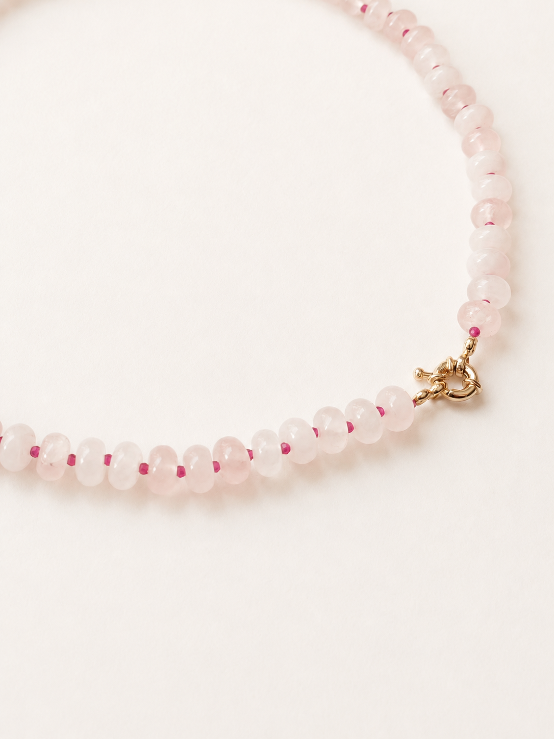 Close-up of pale pink rose quartz rondelle beads and stainless steel spring ring clasp