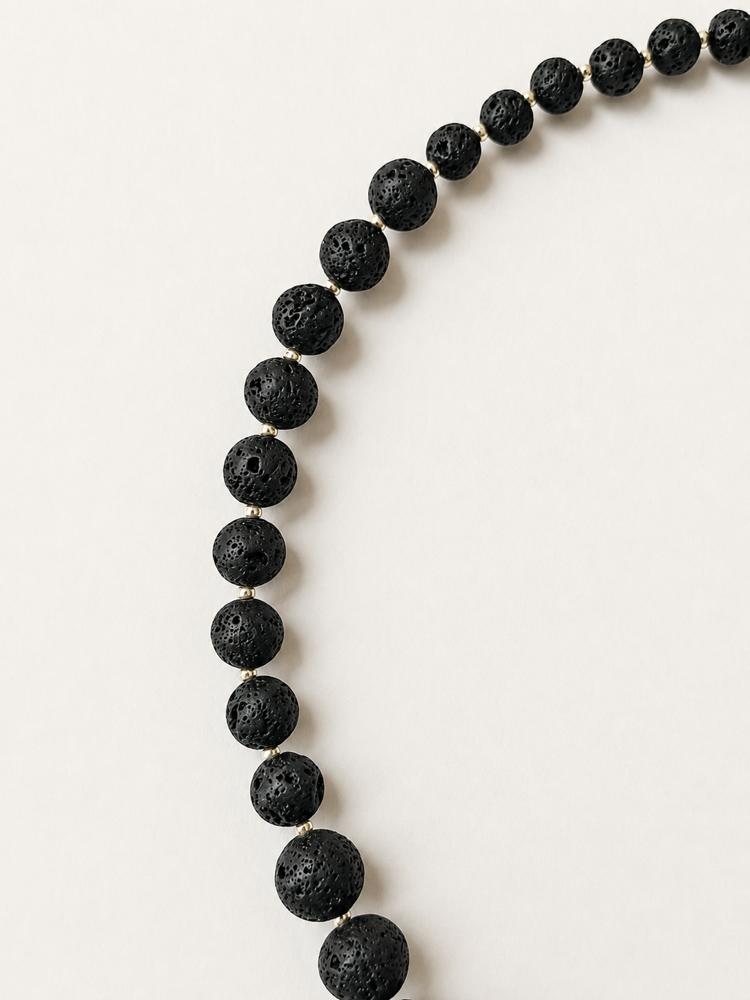 Close-up of porous black lava stone beads increasing gradually in size