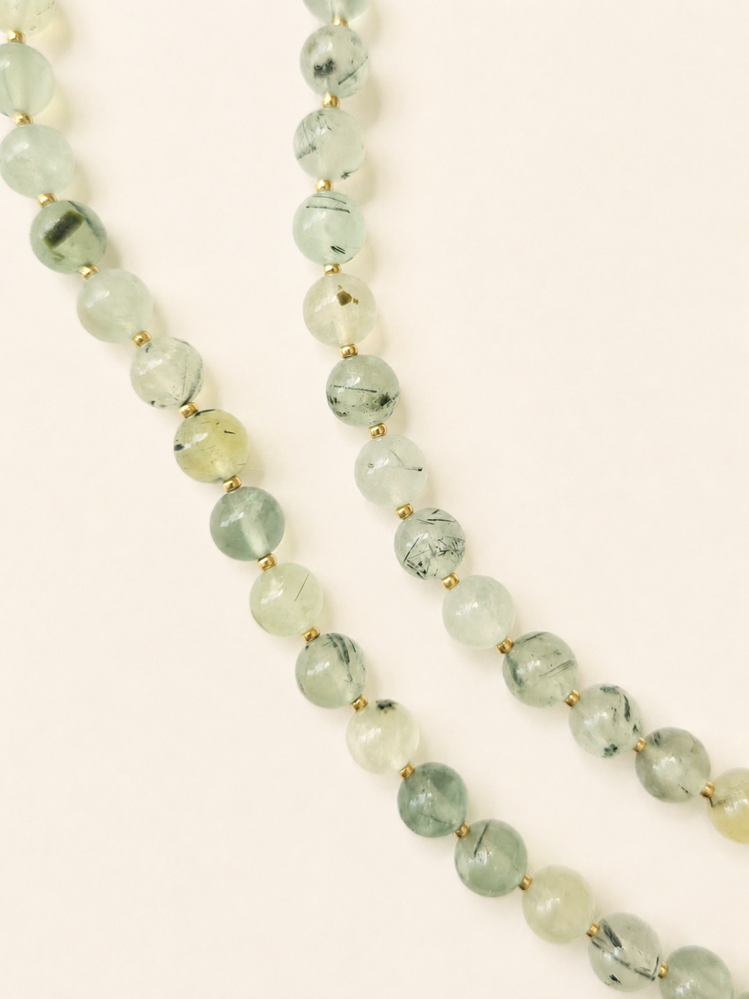 Detailed view of translucent prehnite beads in green and yellow tones with gold accents
