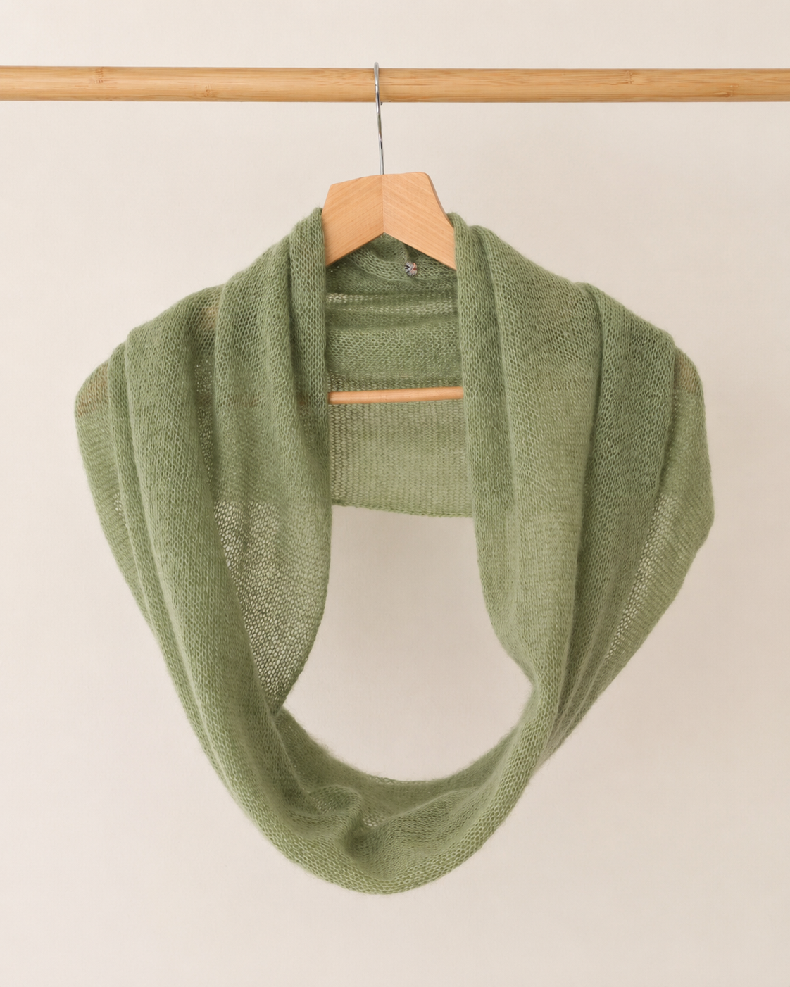 Soft Sage silk mohair infinity scarf hanging on a wooden hanger.