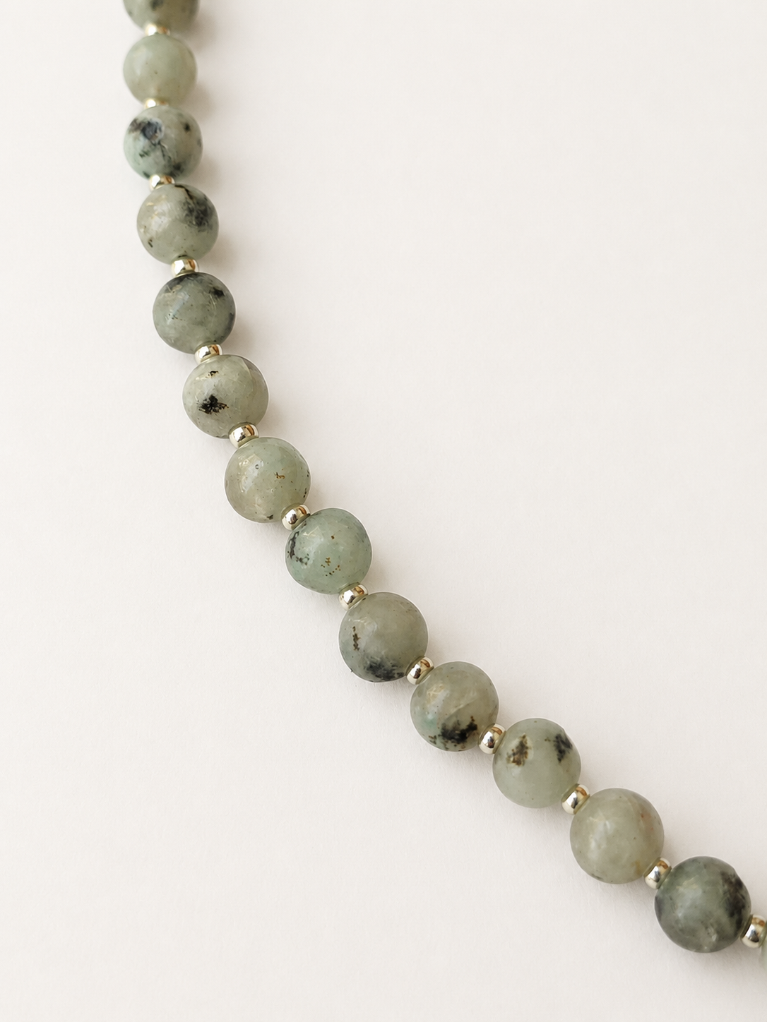 Close-up of pale green kiwi jasper beads with natural black markings and silver Miyuki accents