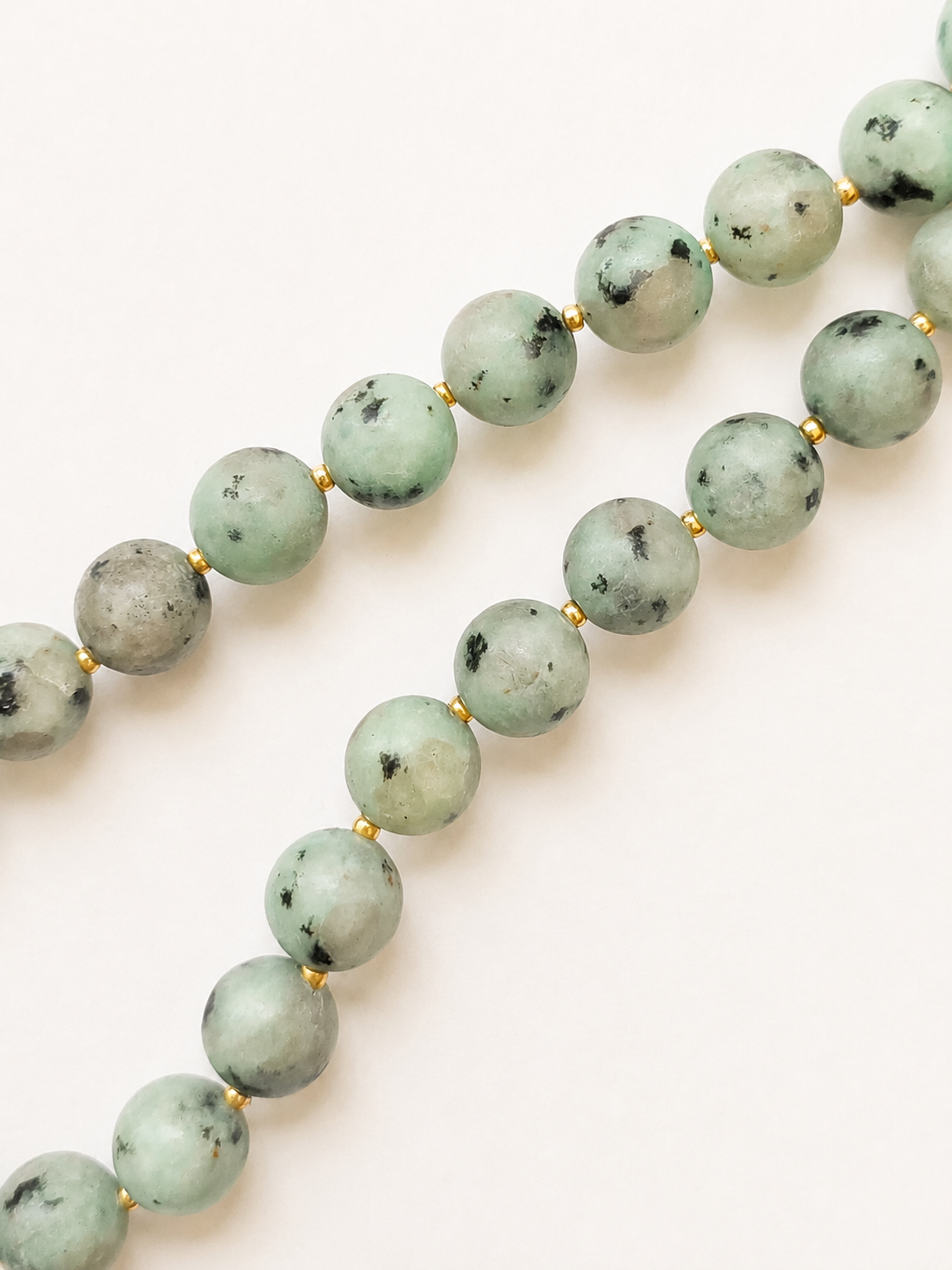 Macro view of natural kiwi jasper patterns and Japanese Miyuki gold spacer beads