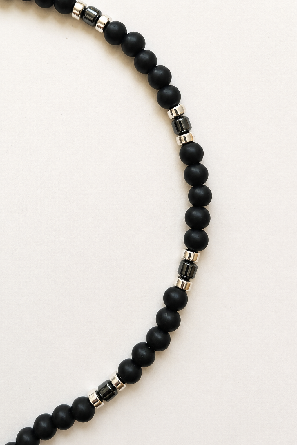 Close-up of 8mm matte black synthetic shungite beads with polished hematite details
