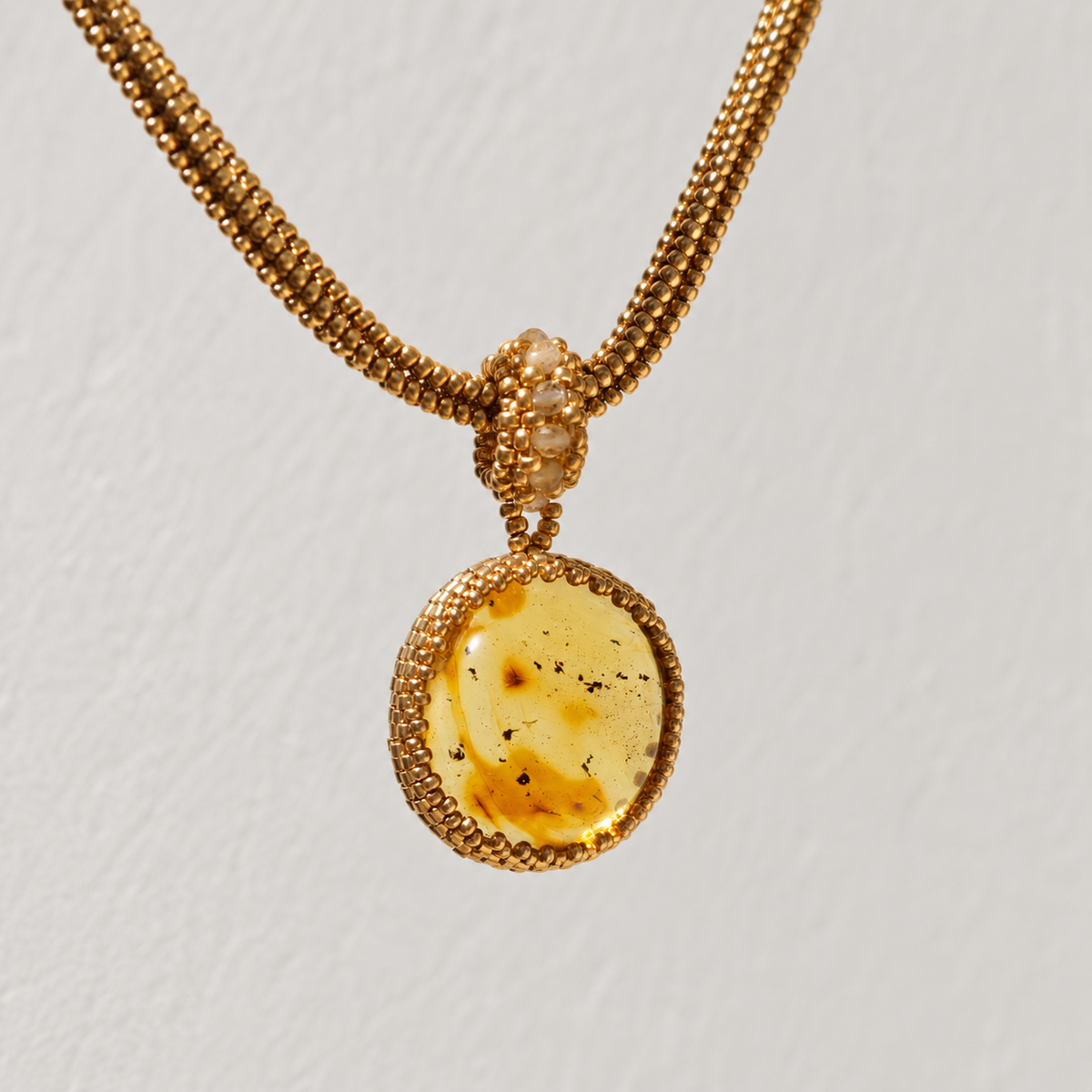 Baltic amber pendant on a gold Miyuki chain shown from a slightly angled front view