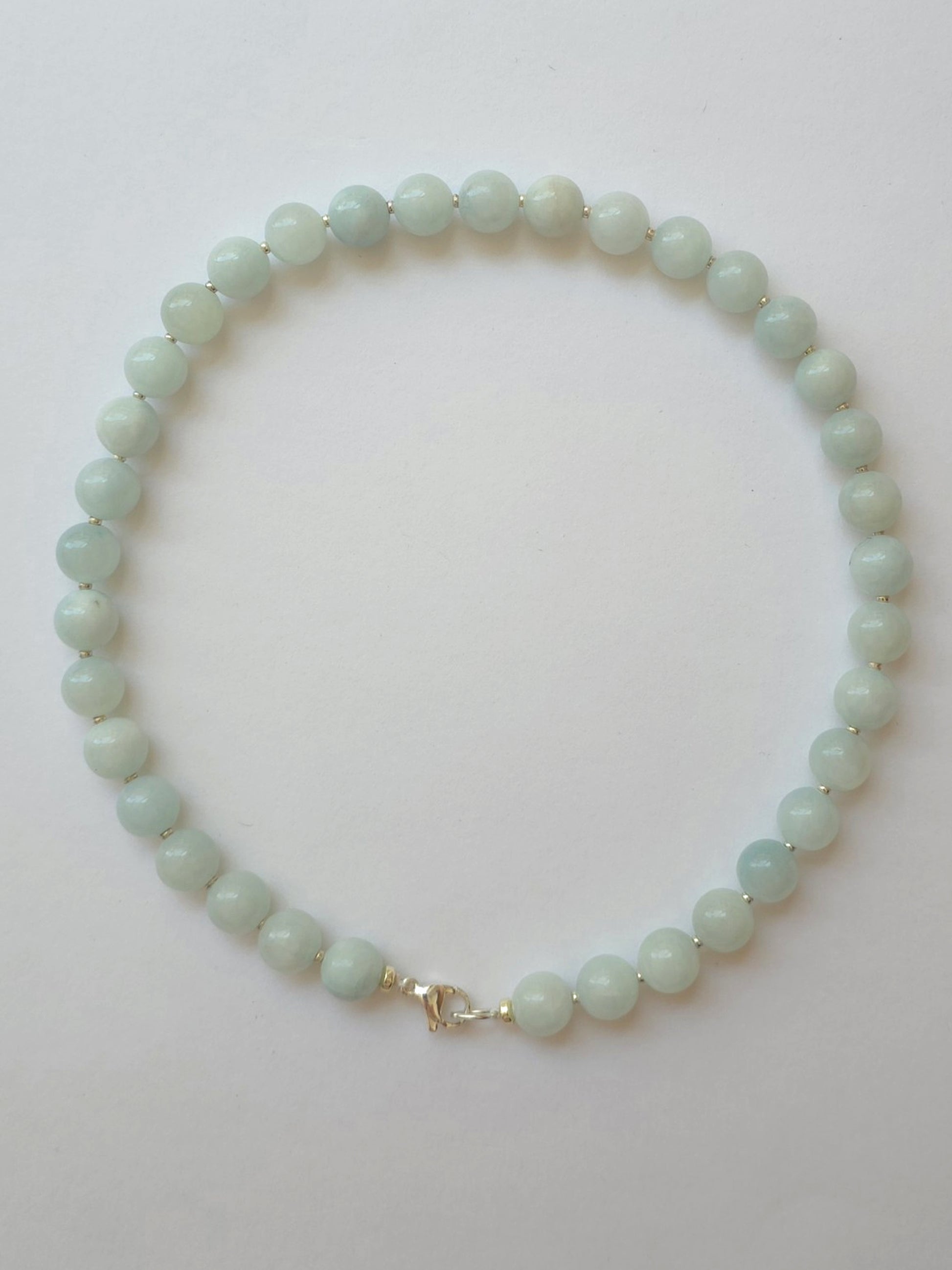 Pale green jadeite necklace with 10mm gemstone beads and silver accents on a light neutral background