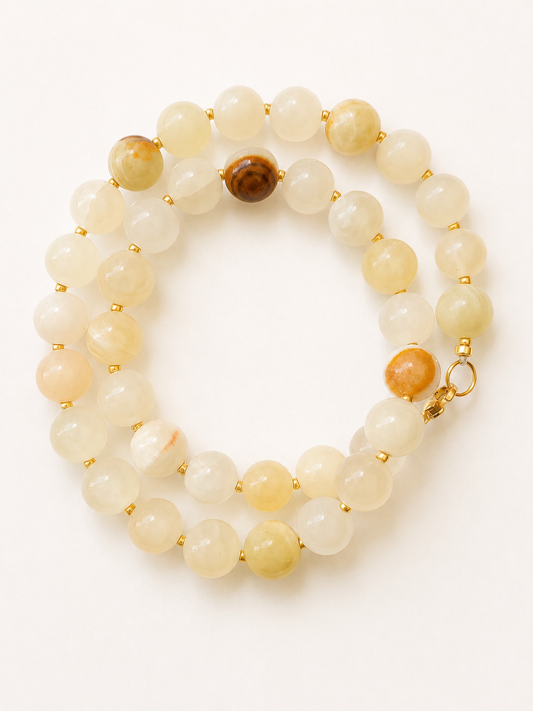 Coiled jadeite necklace showing pale cream, yellow and caramel-toned beads with gold accents