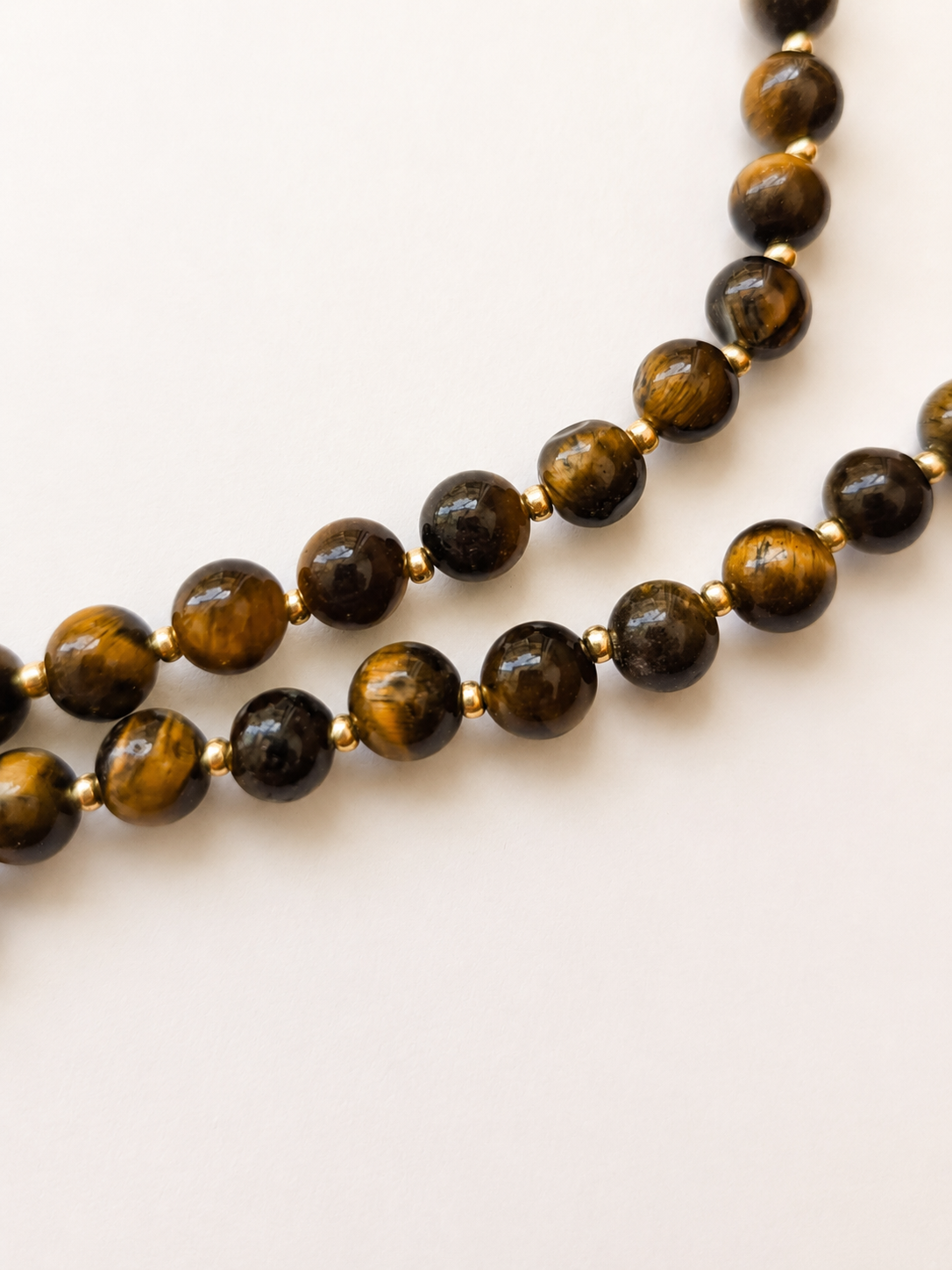 Close-up of polished tiger eye beads with golden bands and Japanese Miyuki spacers