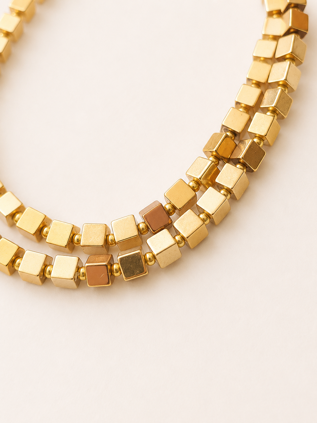 Macro view of gold-coloured hematite cubes with varied metallic reflections and Miyuki spacers