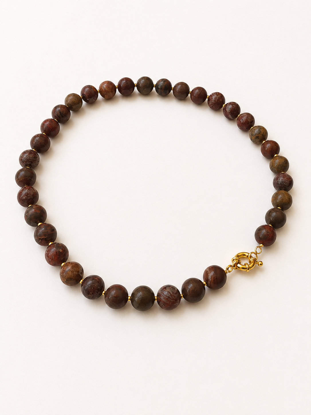 Angled full view of a brown and rust agate bead necklace with a golden spring ring clasp