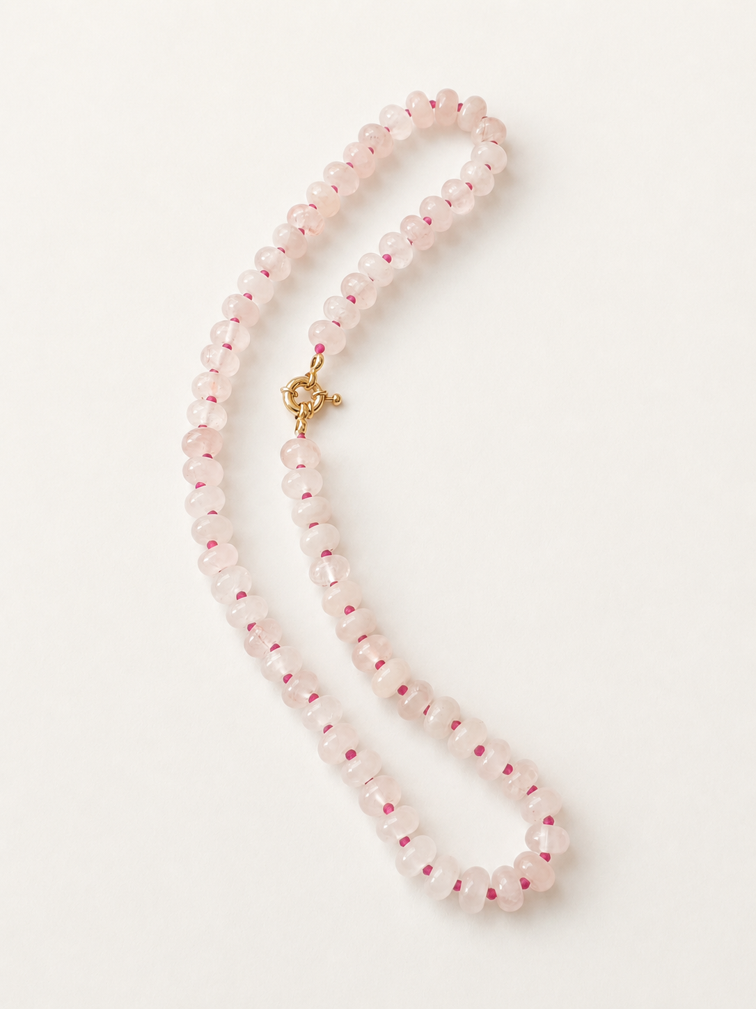 Full 43cm rose quartz necklace arranged in a long oval on a neutral background