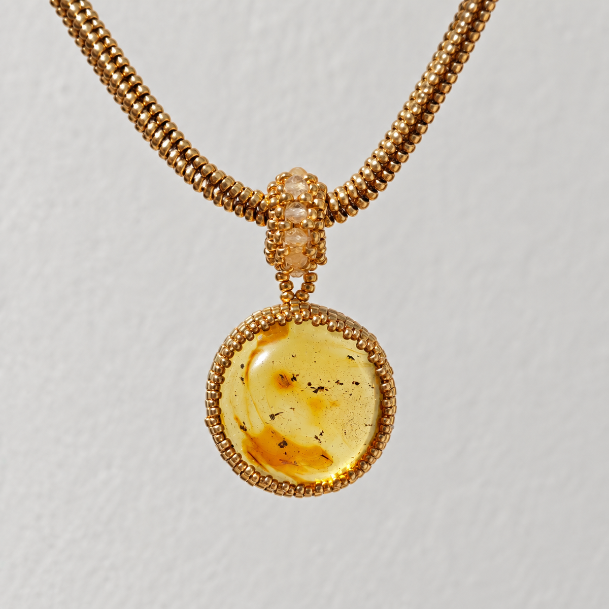 Baltic amber round pendant with natural inclusions on a gold Miyuki beaded chain