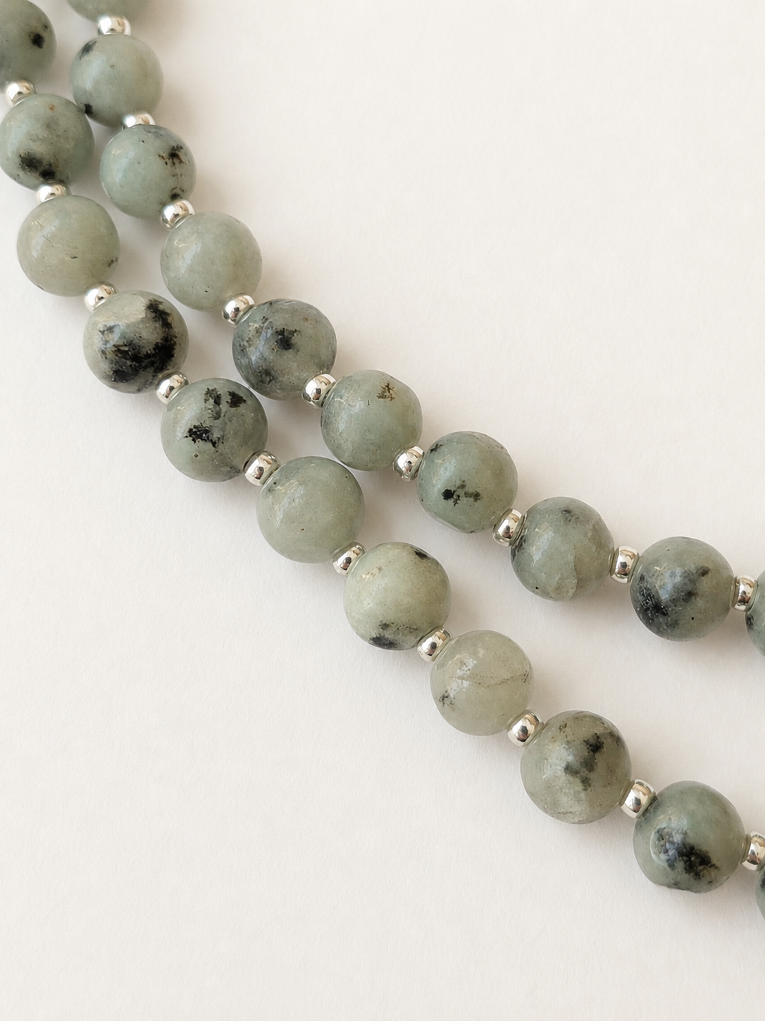 Detailed view of the varied mint, grey-green and black patterns in polished kiwi jasper beads