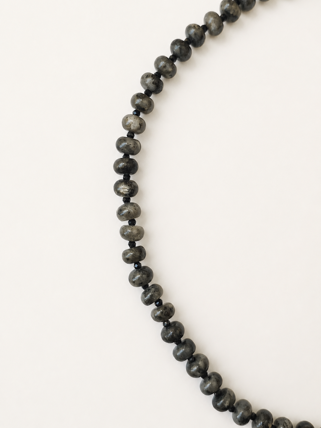 Close-up of grey labradorite rondelles separated by small faceted black spinel beads