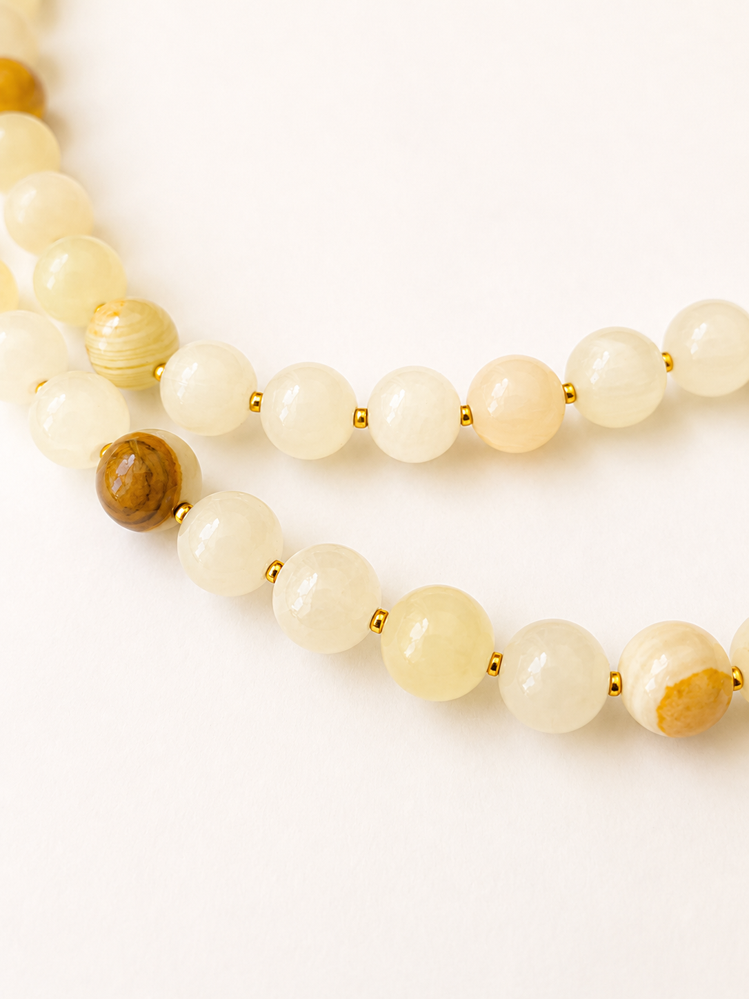 Close-up of cream yellow jadeite beads with natural honey markings and gold Miyuki spacers