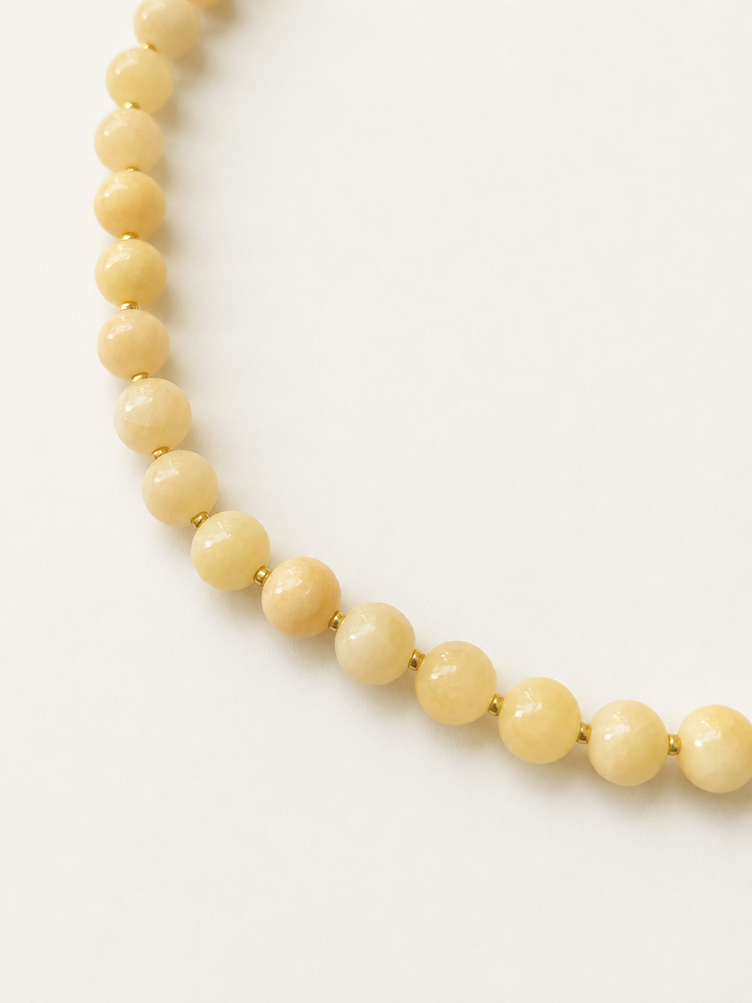 Close-up of light peach jadeite beads with gold Japanese Miyuki spacers