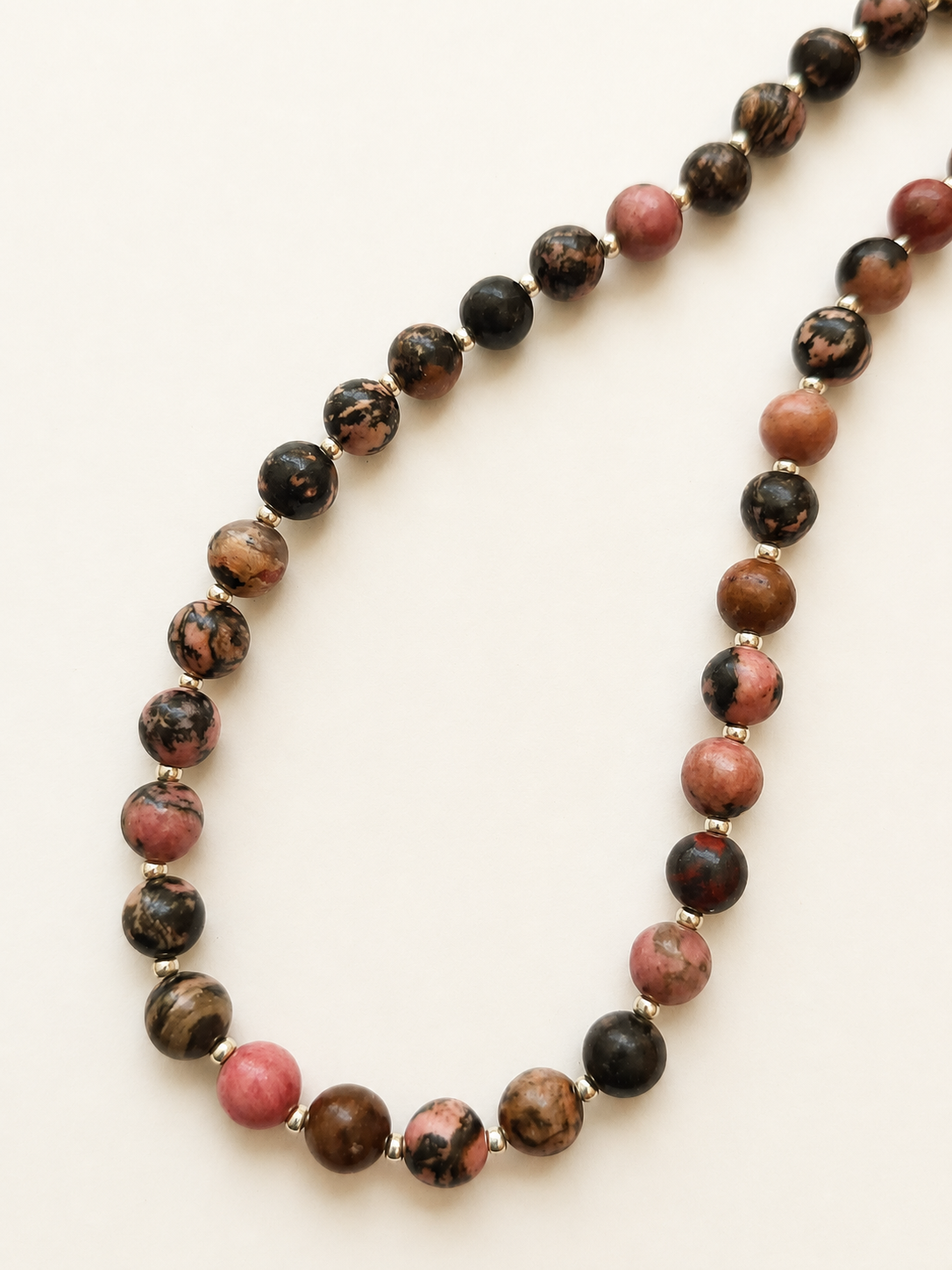 Detailed view of varied pink, brown and black rhodonite beads in a 43.5cm necklace