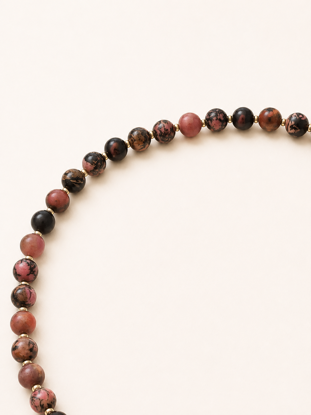 Close-up of pink and black patterned rhodonite beads separated by silver Miyuki spacers