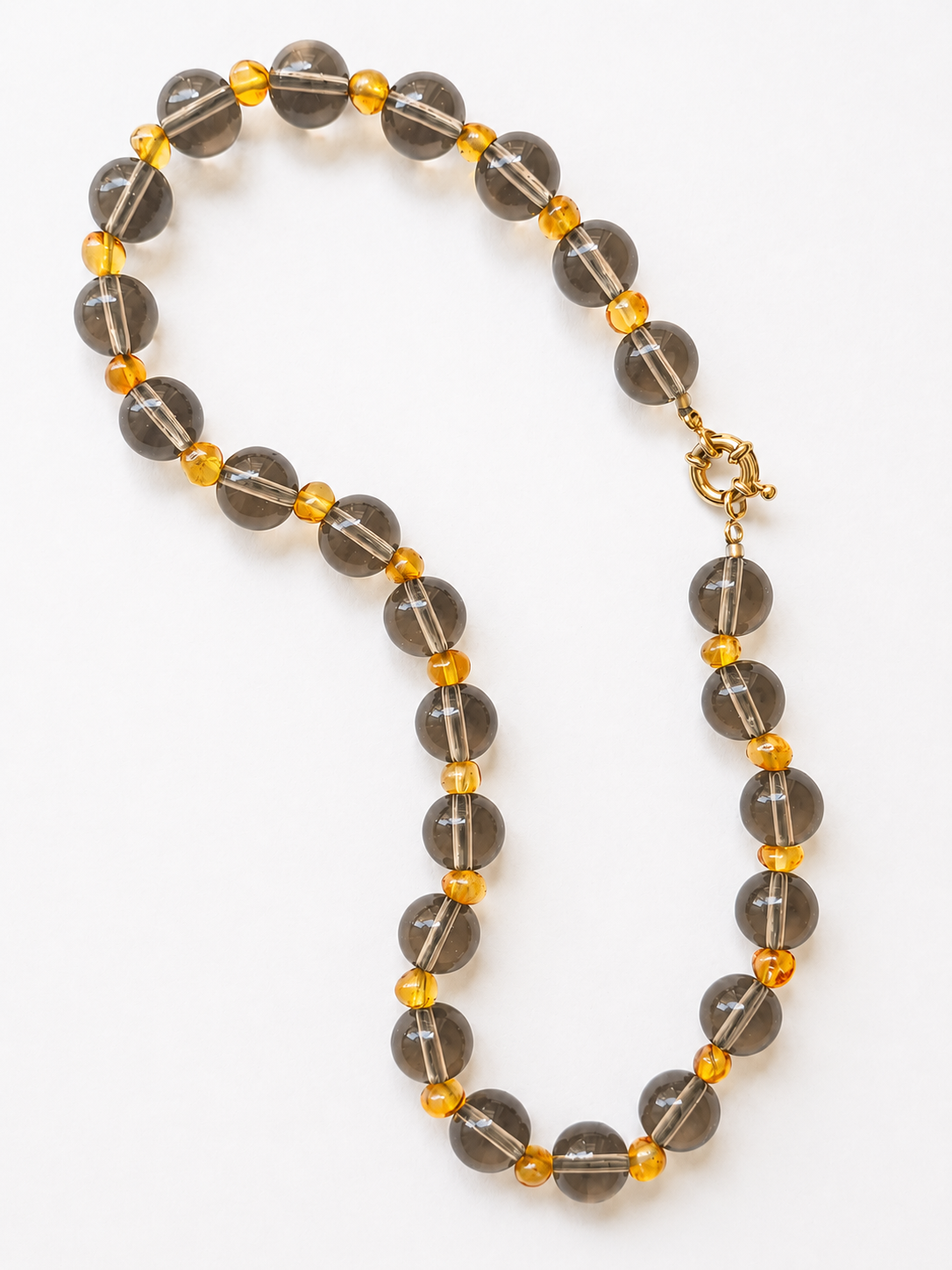 Handmade smoky quartz and amber necklace displayed in an elongated arrangement with golden clasp