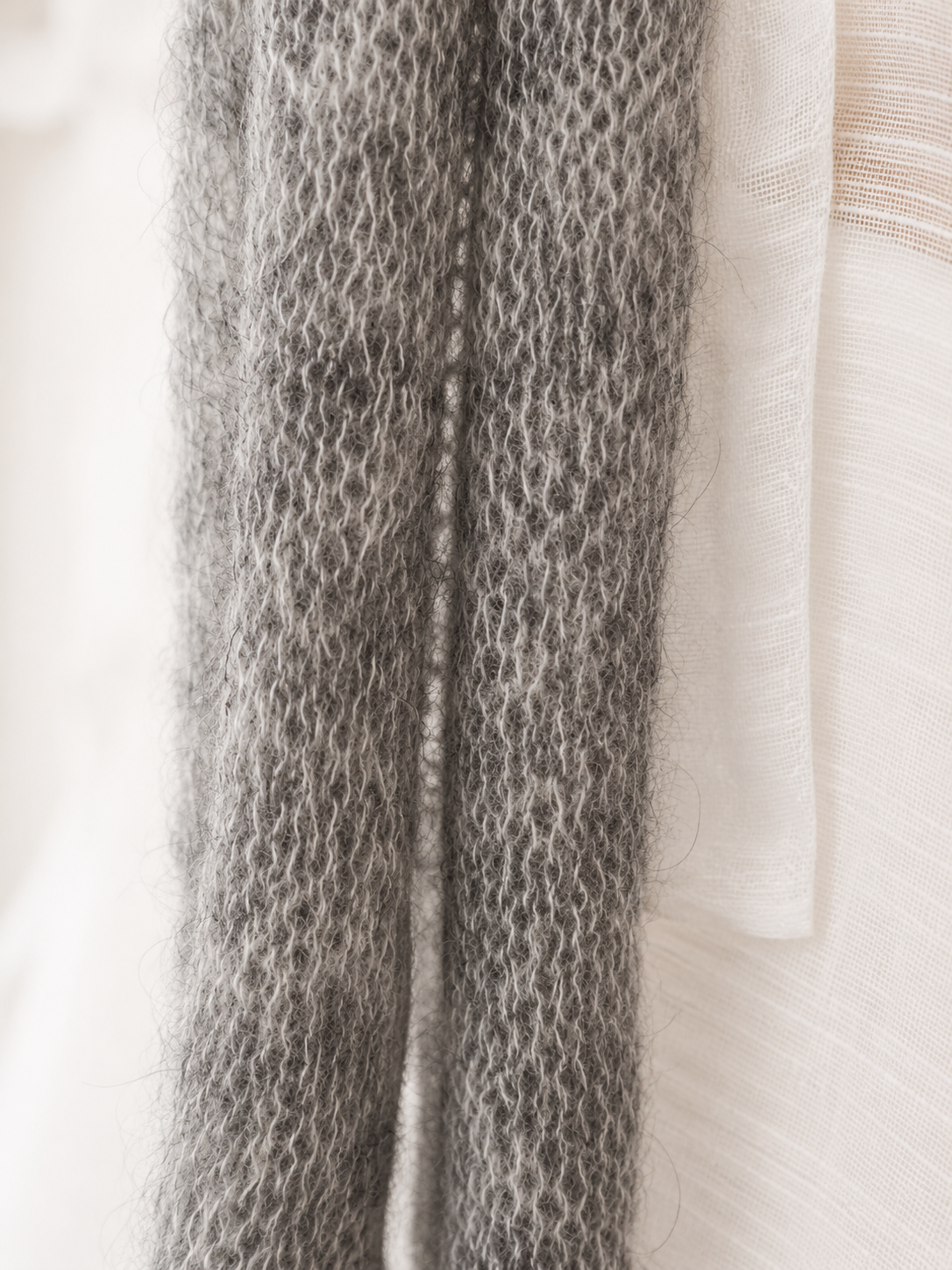 Macro detail of the delicate open-knit texture of a handmade mohair silk scarf.