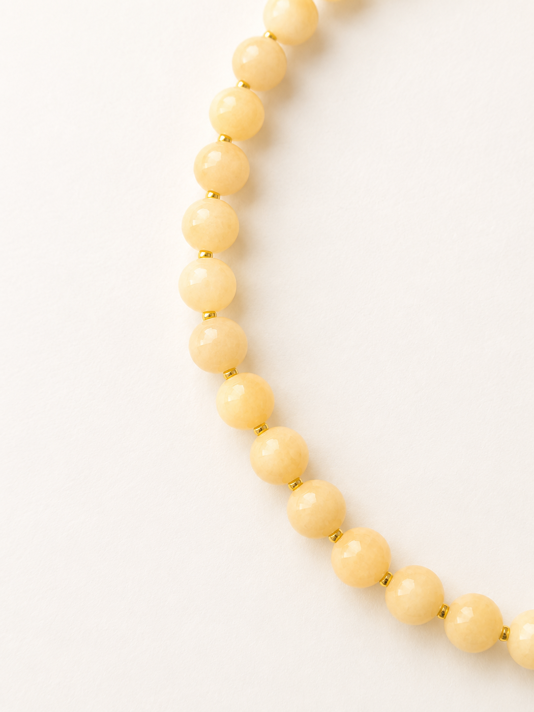 Curved detail of light peach jadeite necklace showing natural colour variations