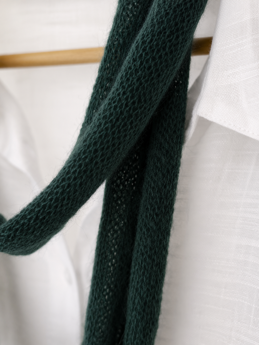 Close-up of the delicate knit structure of a forest green mohair scarf.