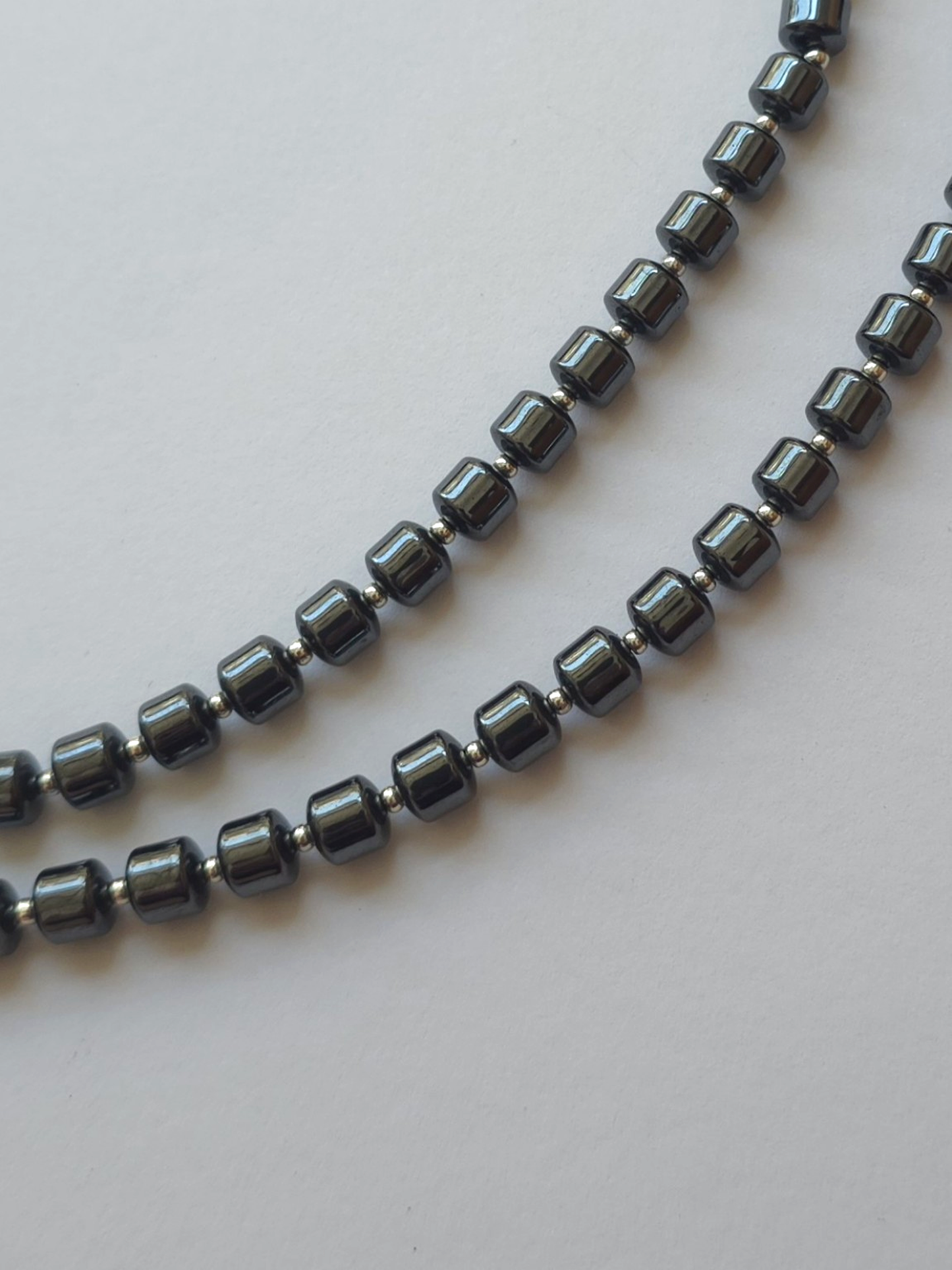Detailed view of gunmetal hematite beads and silver accents in two necklace rows