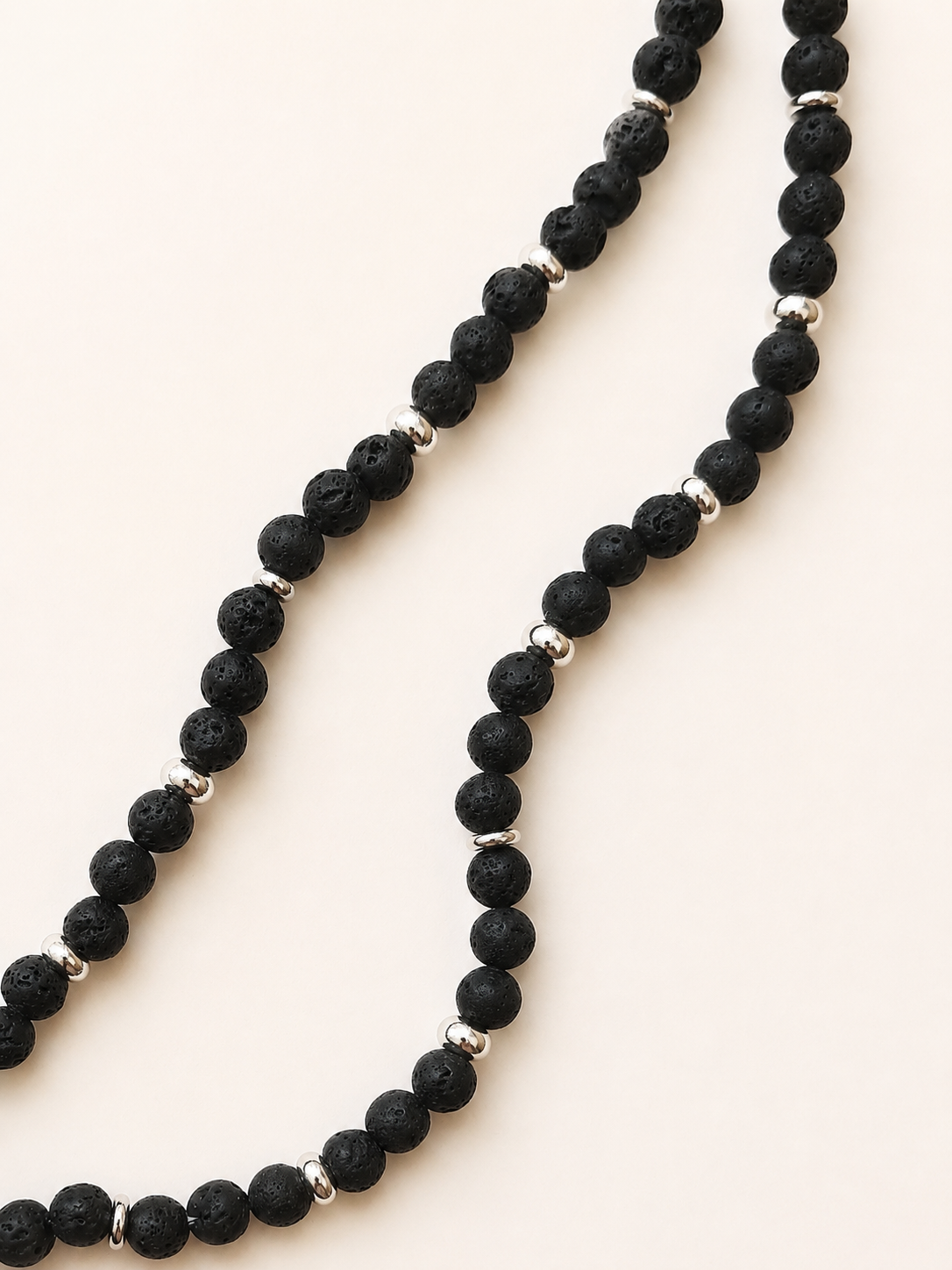 Close-up of porous black lava beads and polished silver-coloured spacer beads