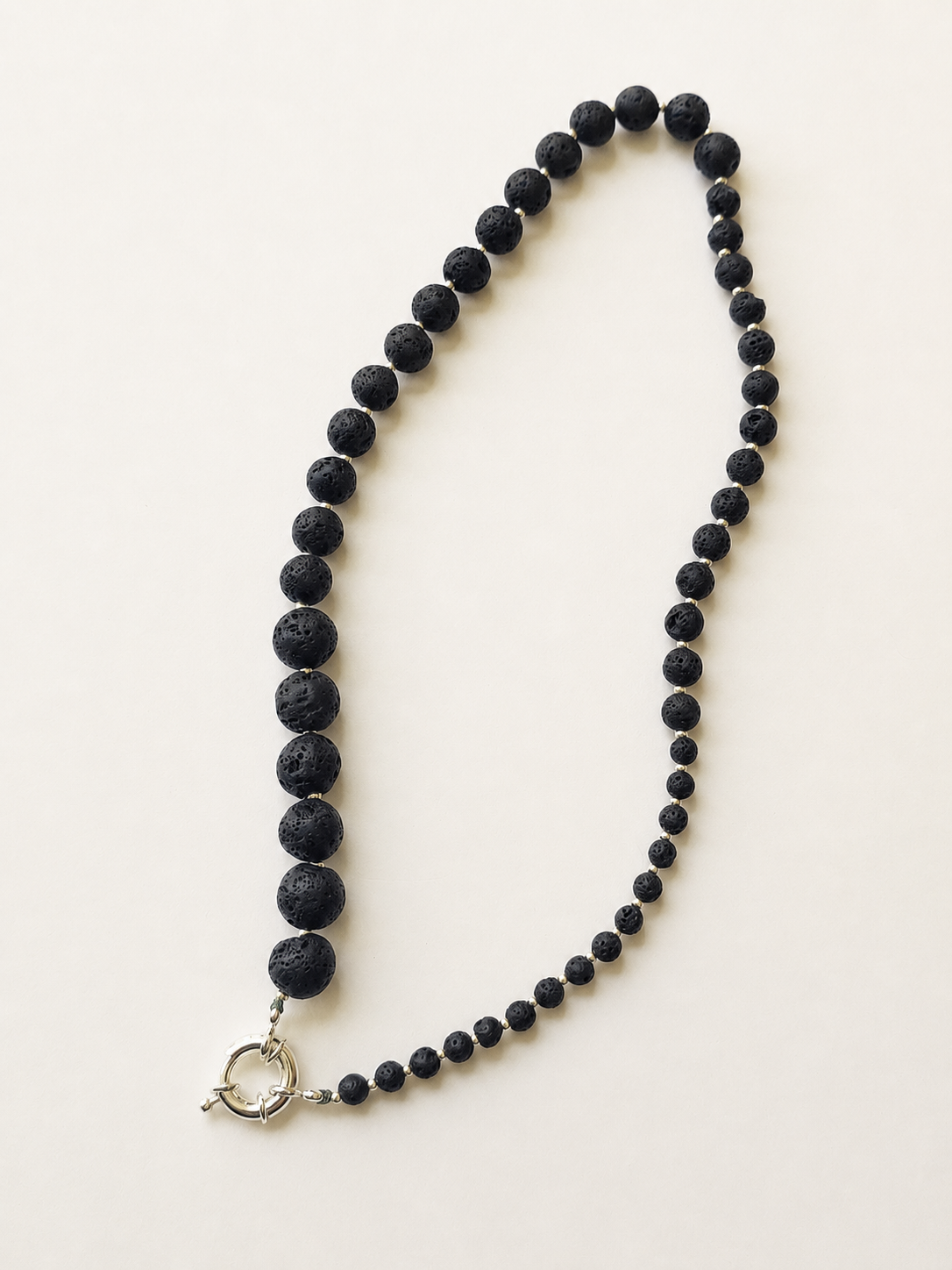 Full 43cm graduated lava stone necklace displayed vertically on a warm ivory background