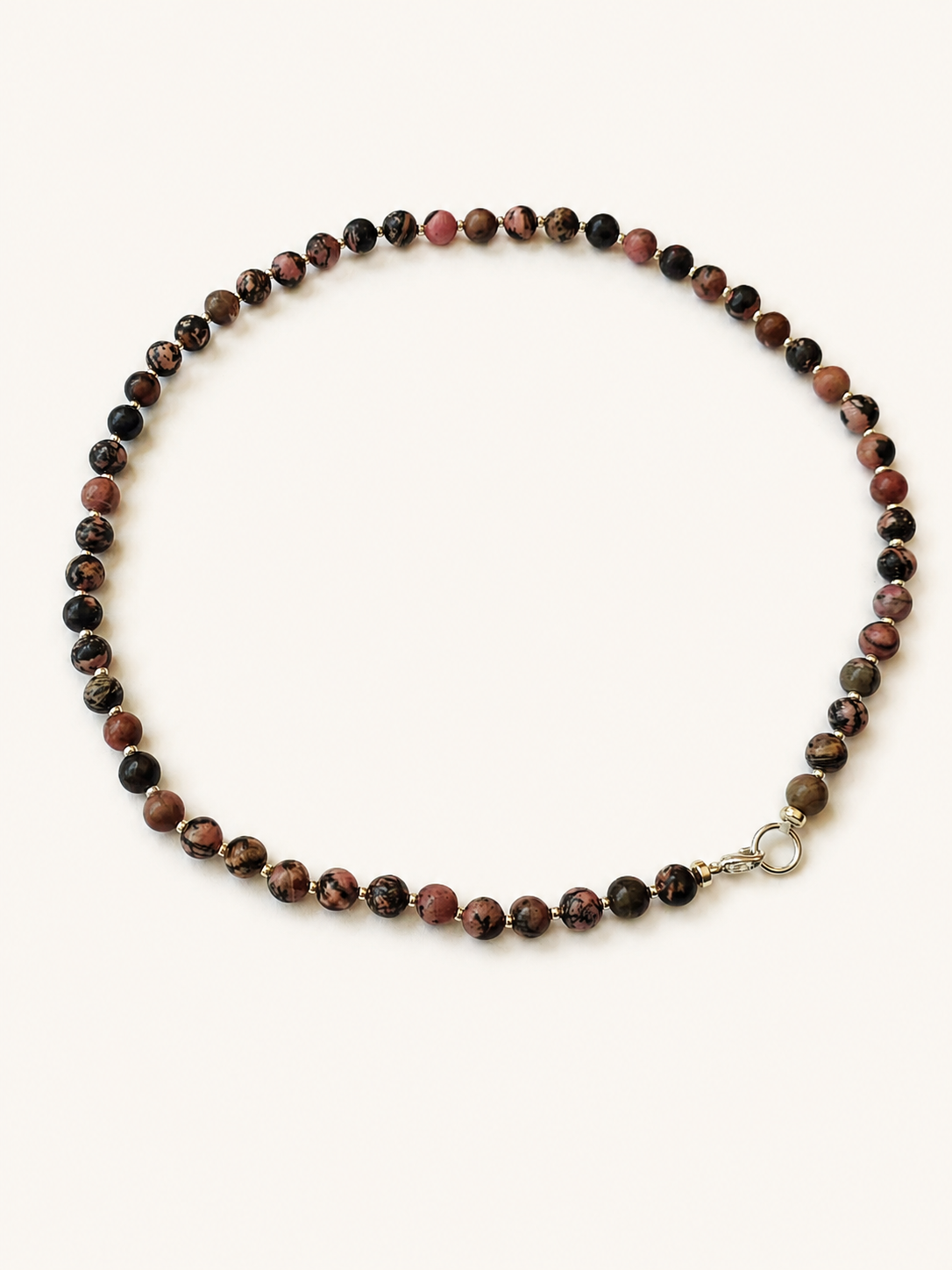 Angled full view of a patterned rhodonite bead necklace with silver-coloured details