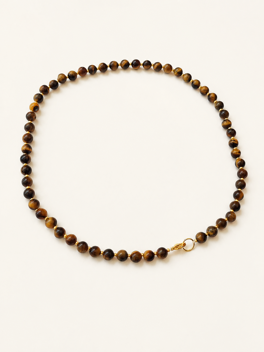 Angled full view of a polished tiger eye bead necklace with warm golden details